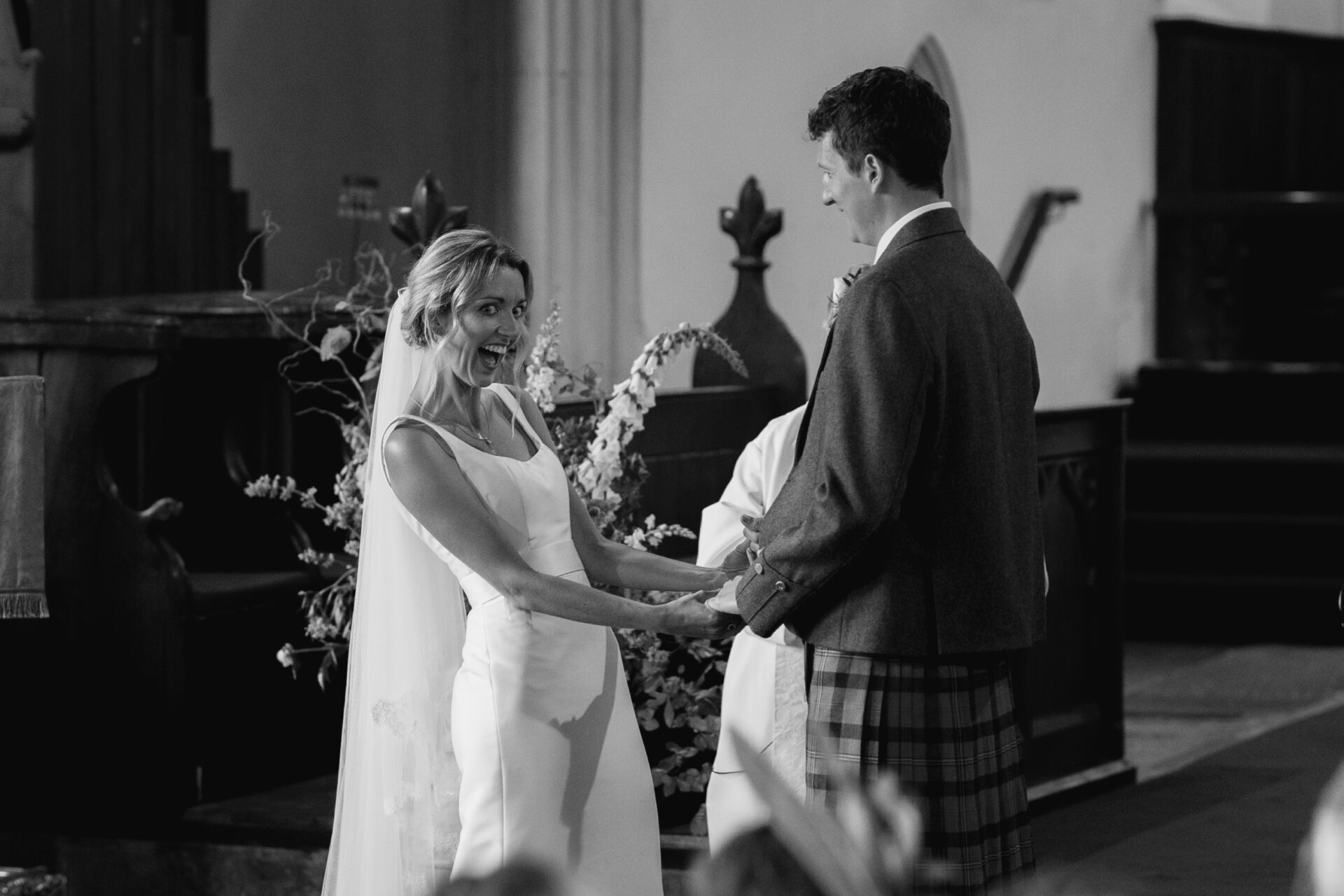 The bride and groom share a laugh with their guests during their Devon church wedding ceremony
