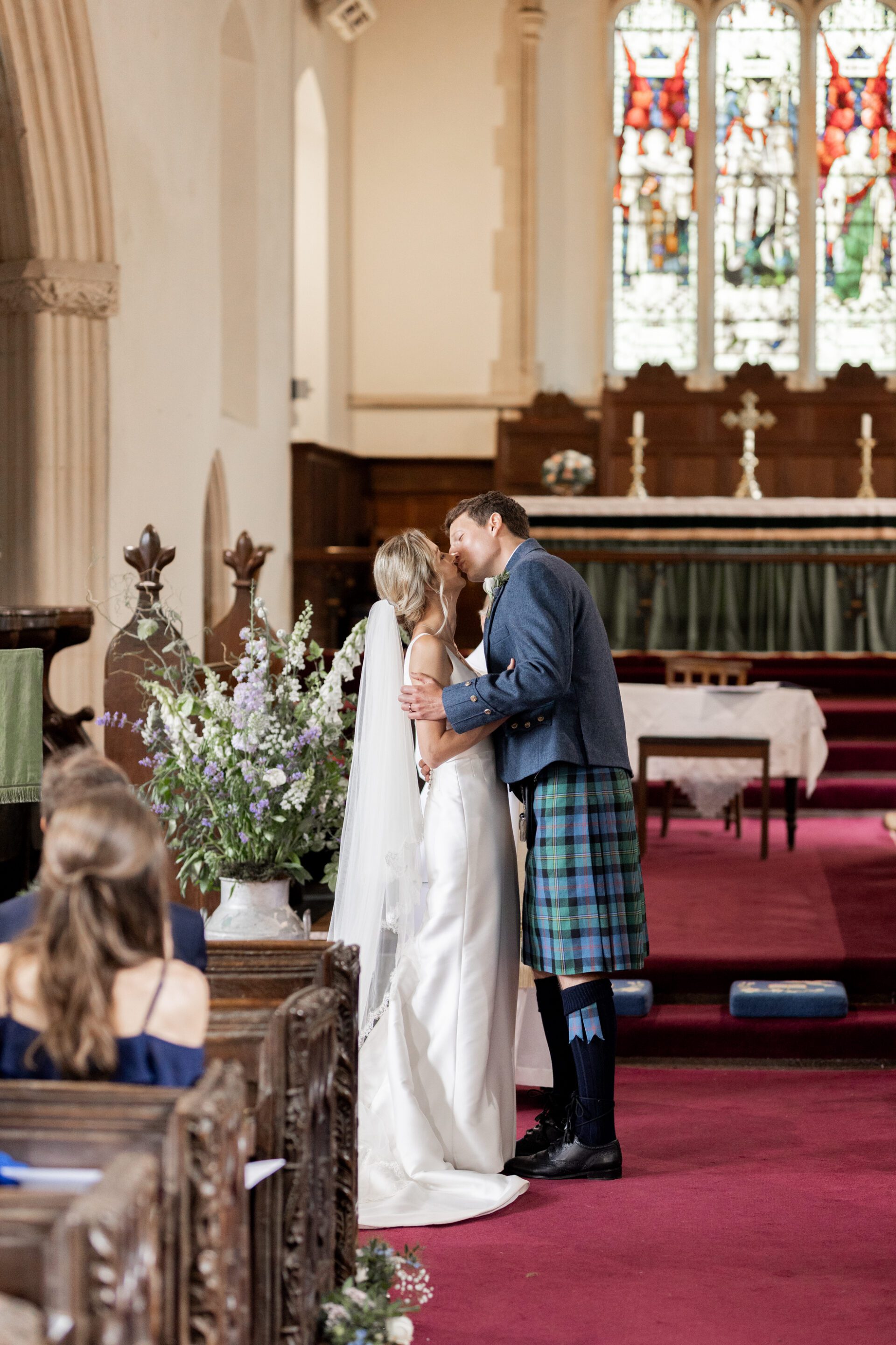 The bride and groom share their first kiss during their Devon church wedding ceremony
