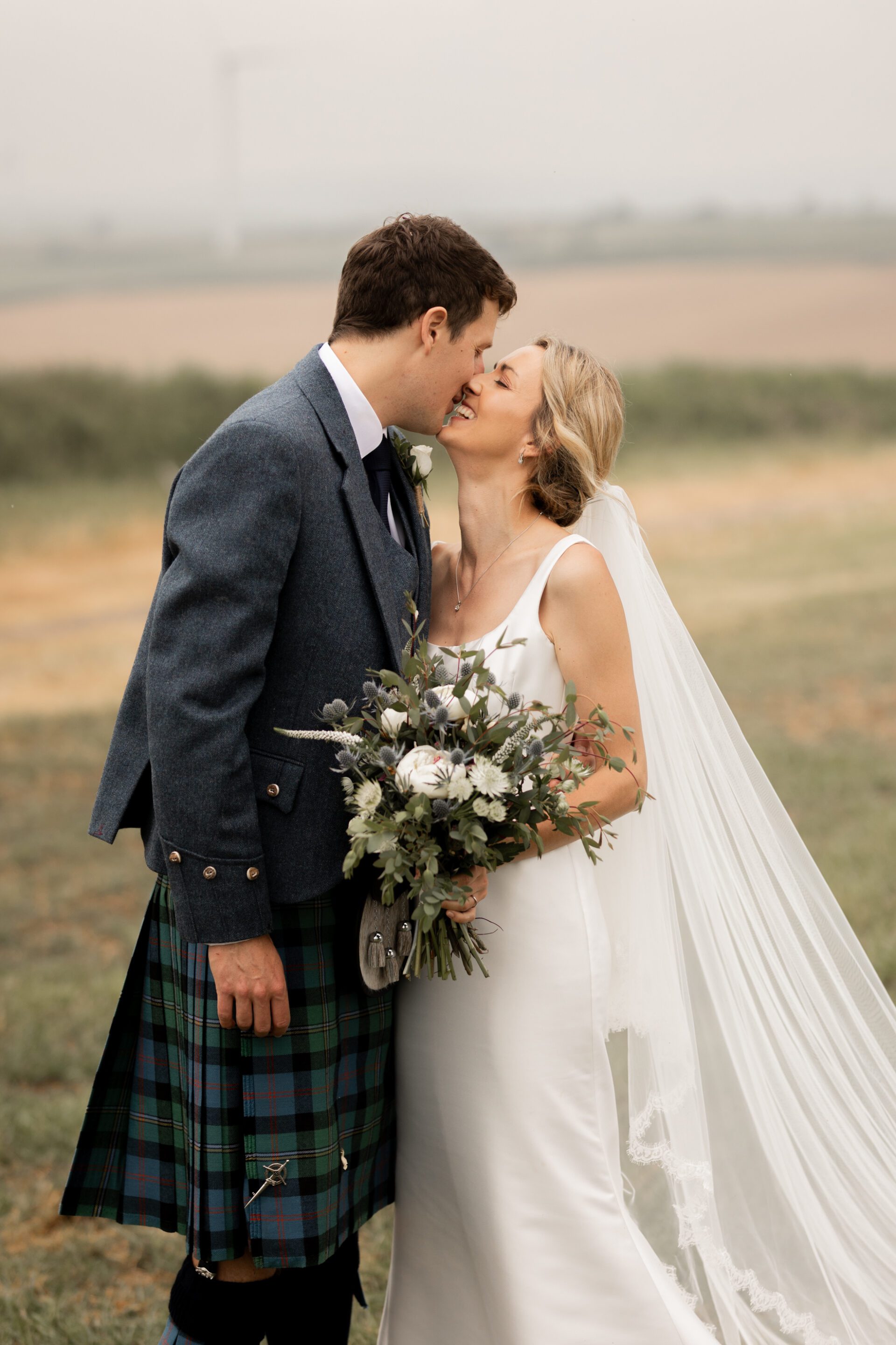 The bride and groom share a kiss after their Devon church wedding ceremony