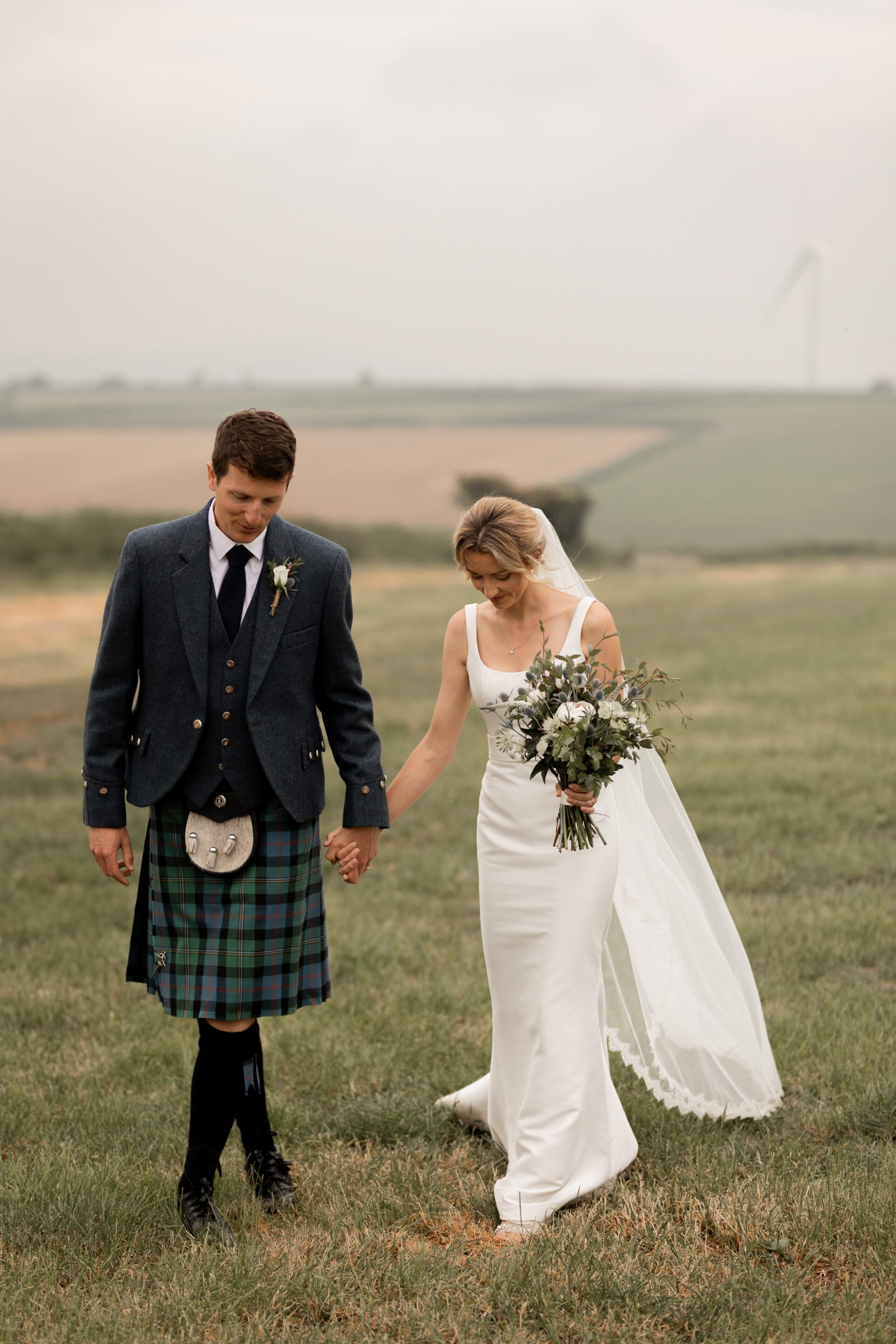 The bride and groom walk hand in hand during their Devon wedding couple portraits
