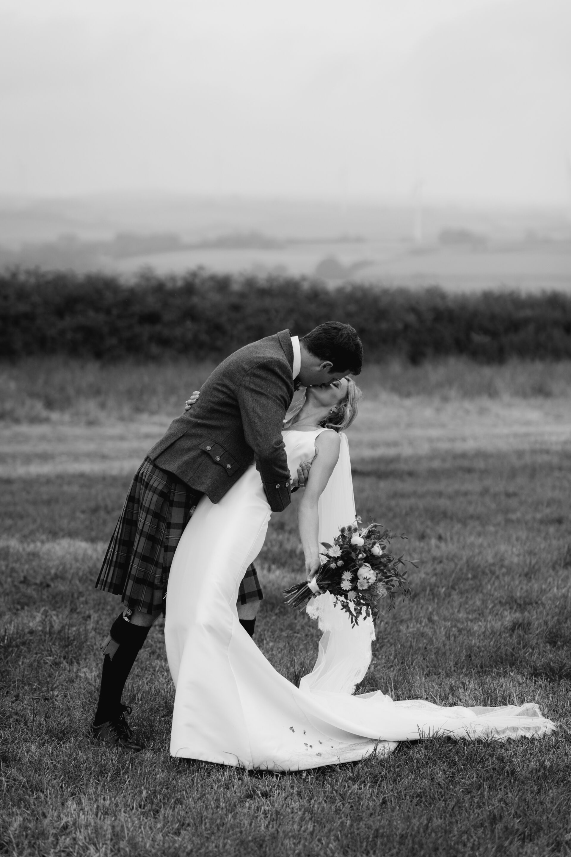 The bride and groom share a drop kiss during the couples portrait session