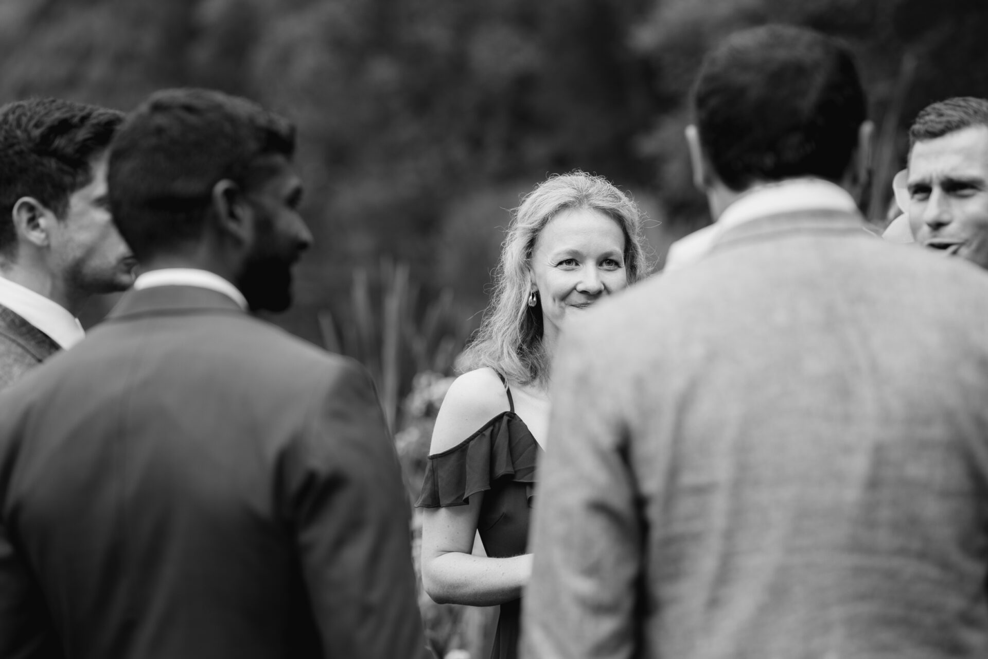 A bridesmaid talks with other guests at the outdoor drinks reception