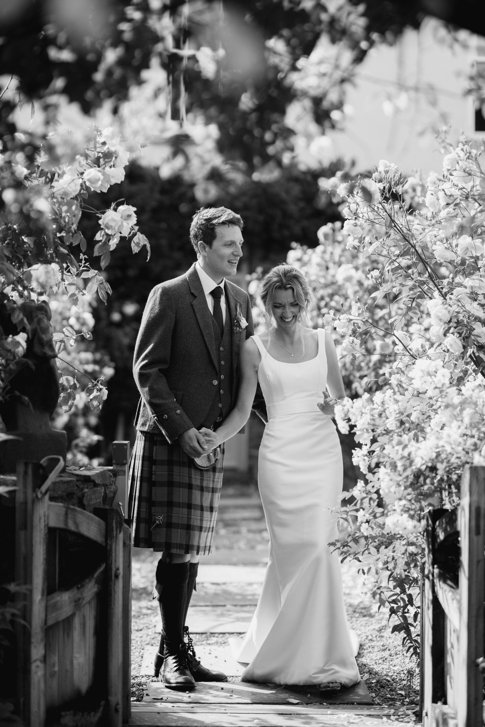 The bride and groom walk amongst the flowers at their English garden party wedding