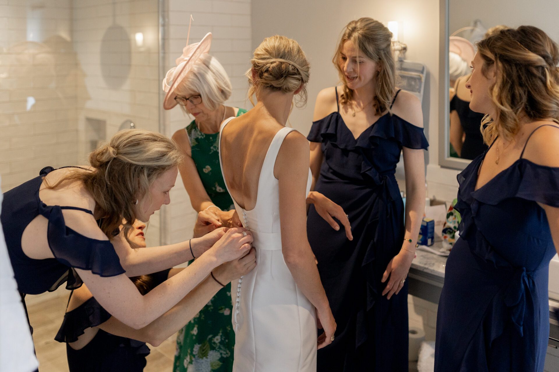 The bridal party help the bride into her Emma Victoria Payne wedding dress