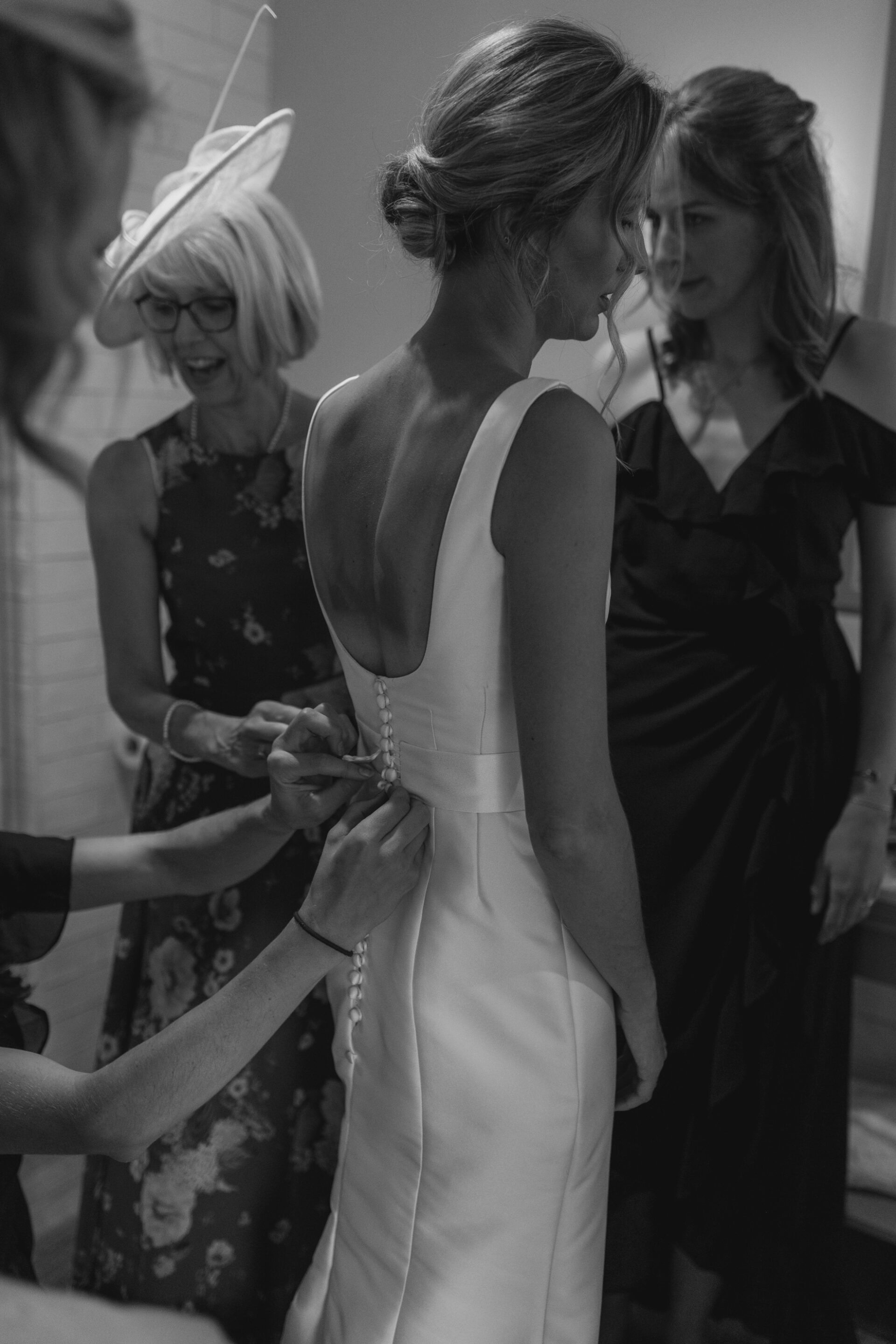 The bridal party help the bride into her Emma Victoria Payne wedding dress