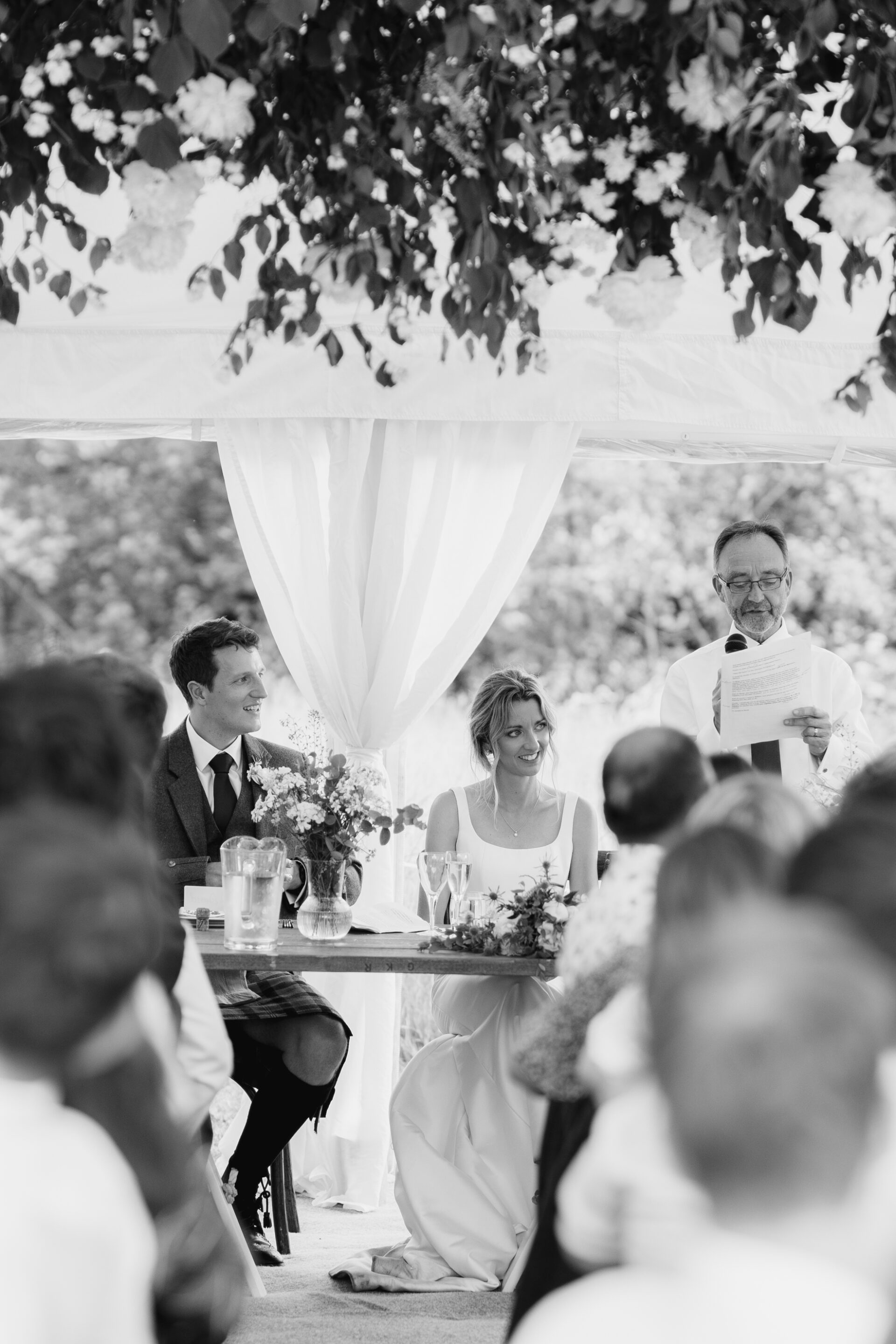 The bride and groom listen to the father of the bride's speech at a Devon marquee wedding