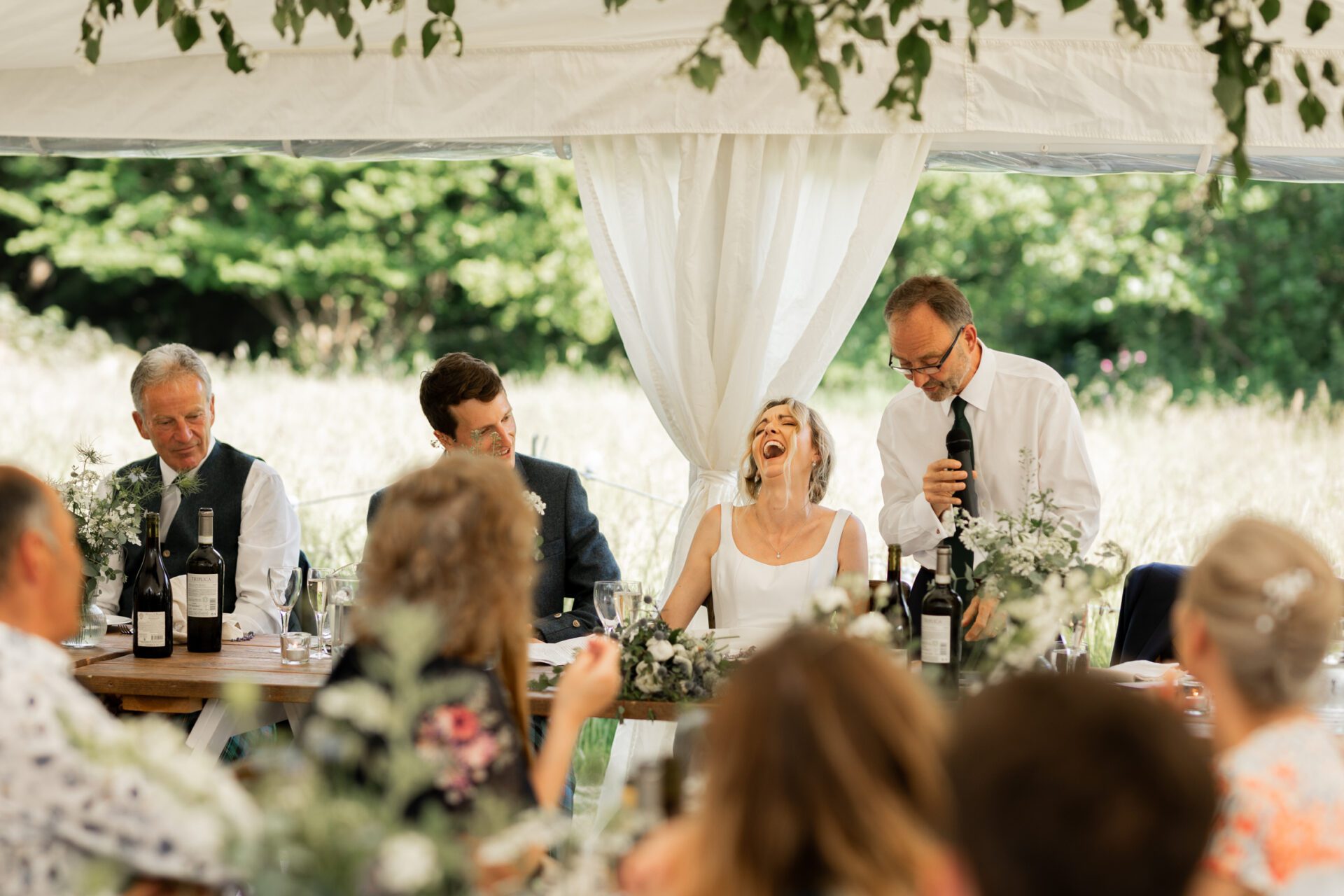 The bride laughs at her father's speech at her Devon marquee wedding