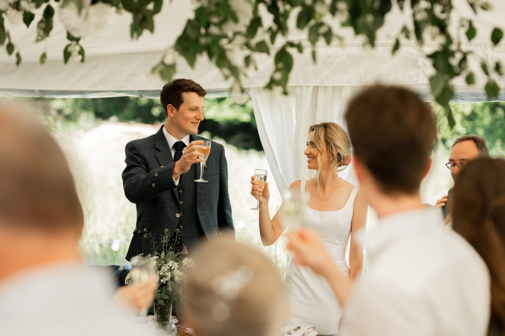 The bride and groom share a toast at their Devon marquee wedding