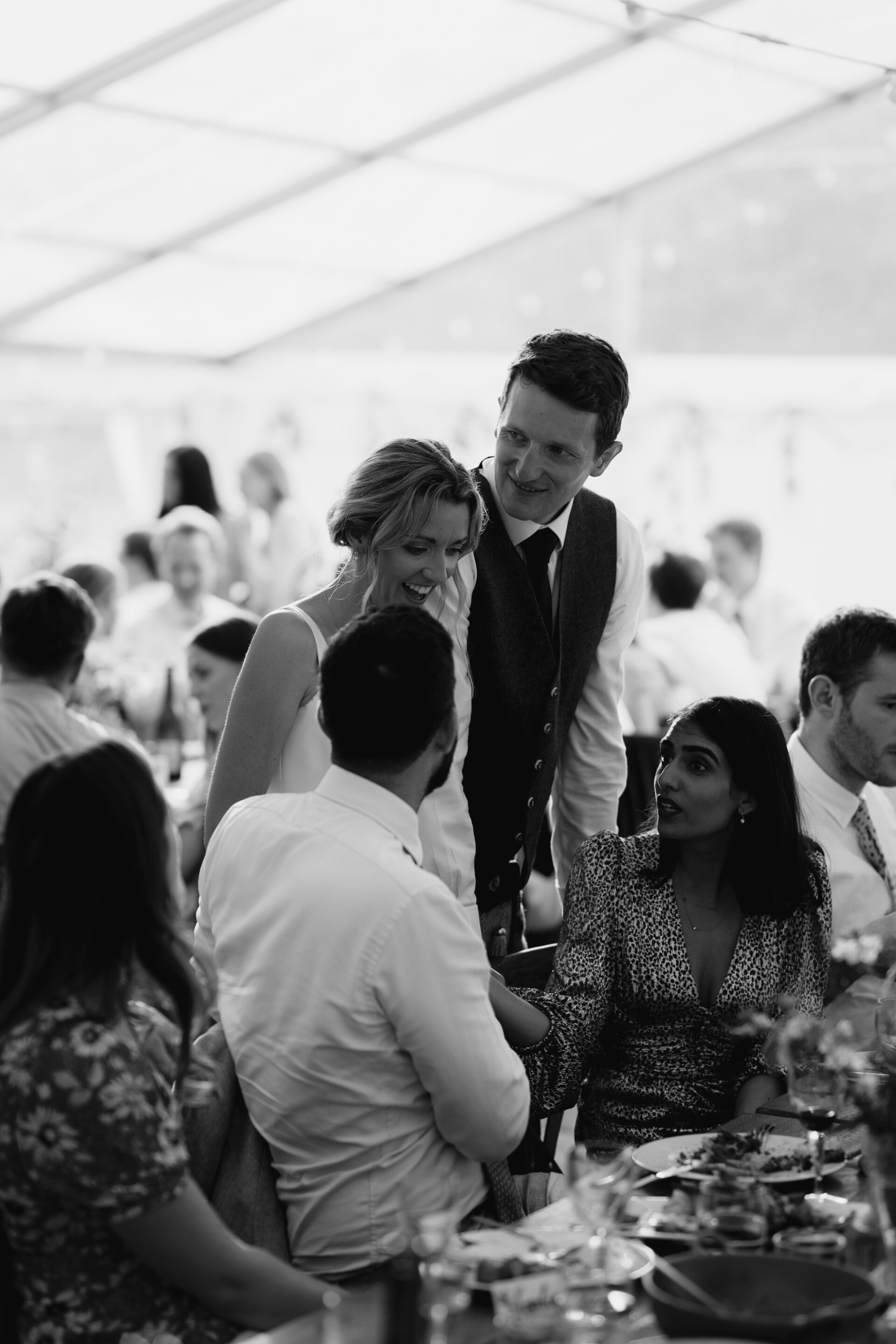 Bride and groom talk to guests during the wedding breakfast at their Devon marquee wedding