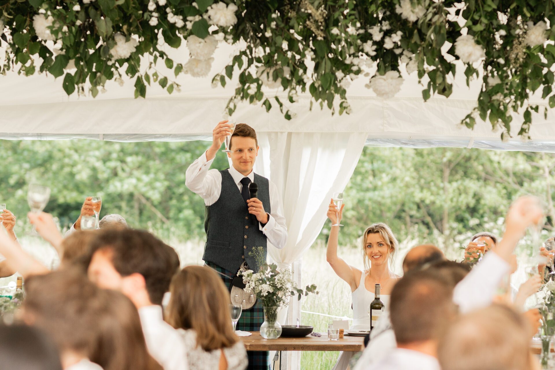 The groom raises a toast at his Devon marquee wedding