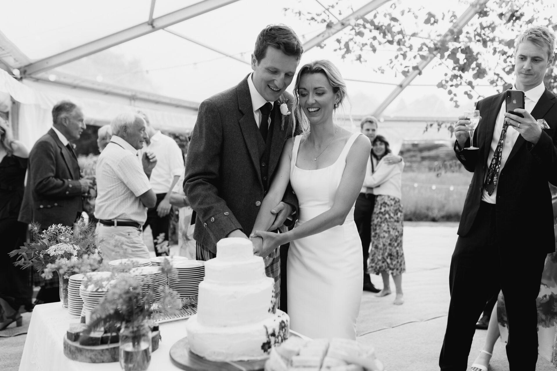 The bride and groom cut the cake at their Devon marquee wedding