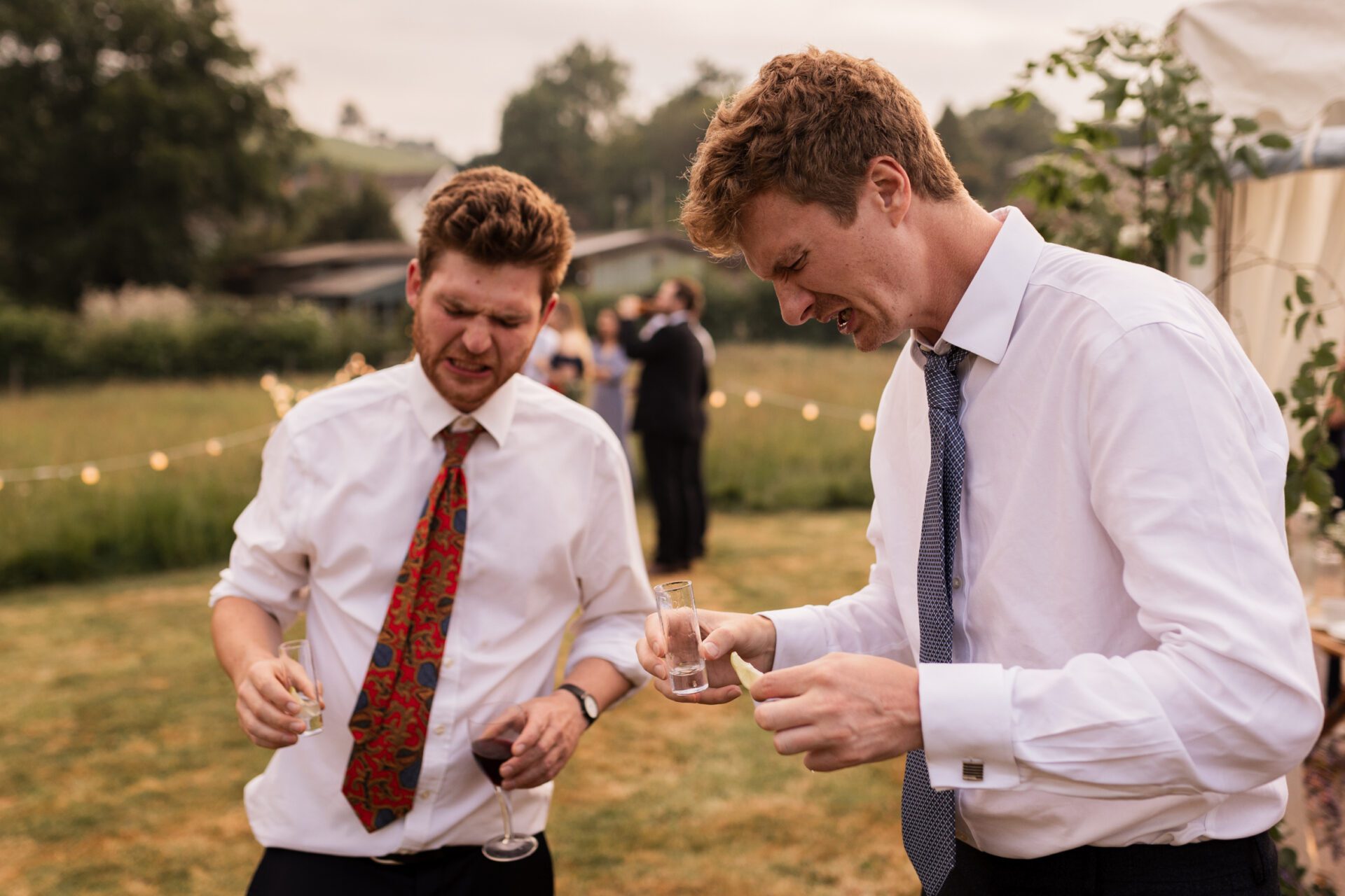 Wedding guests do shots at an outdoor marquee wedding