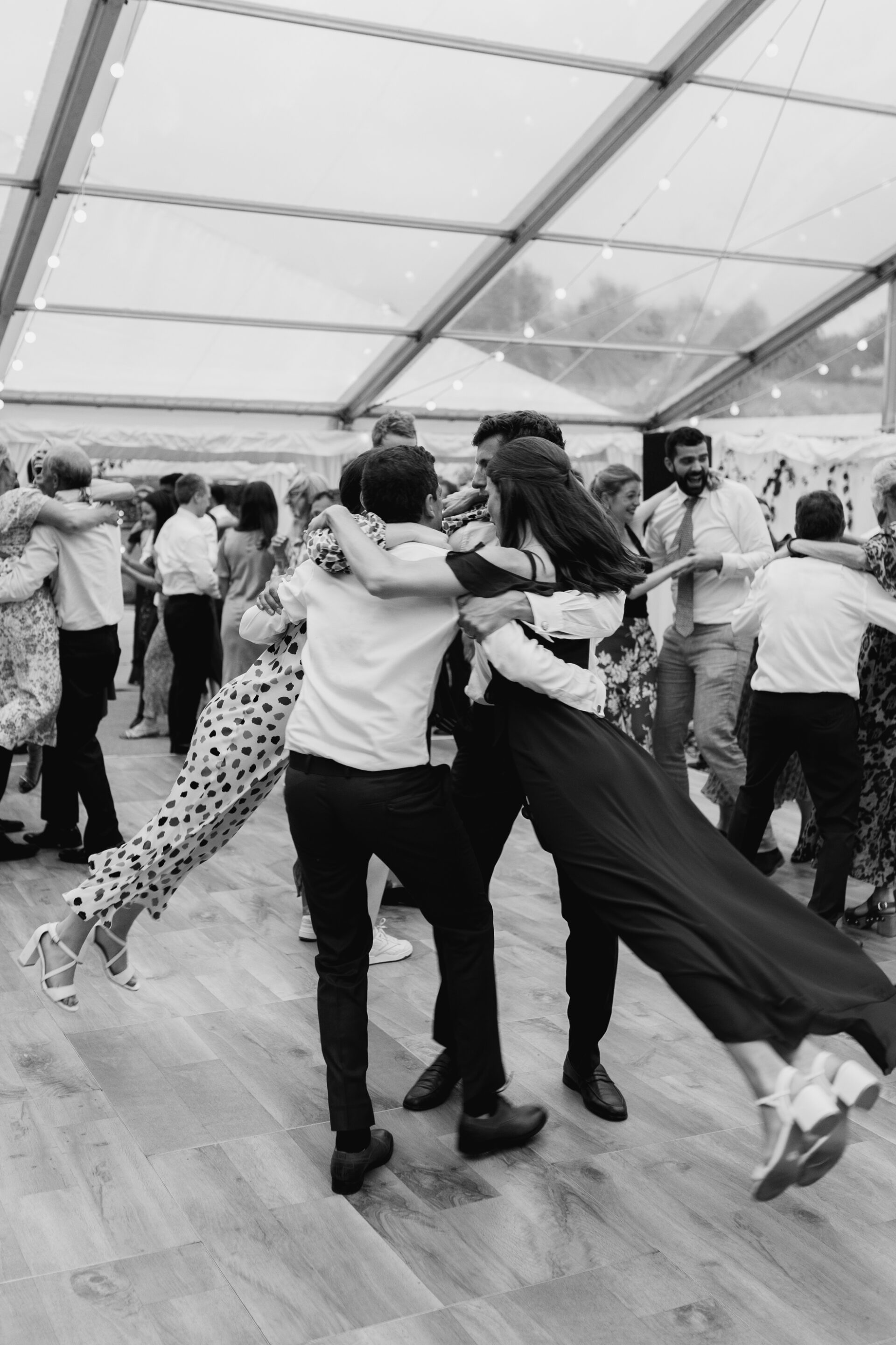 Wedding guests perform a ceilidh at a marquee wedding