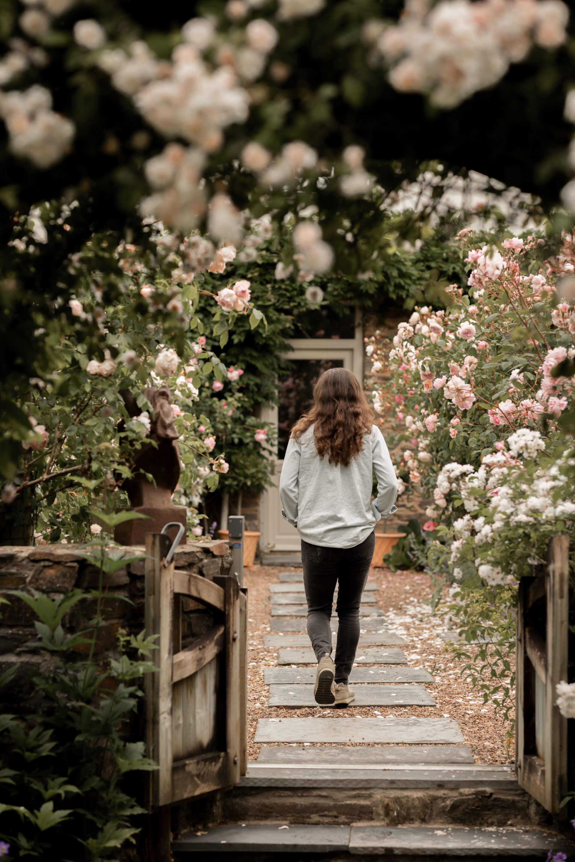 A bridesmaid walks towards the house through the beautiful homegrown roses
