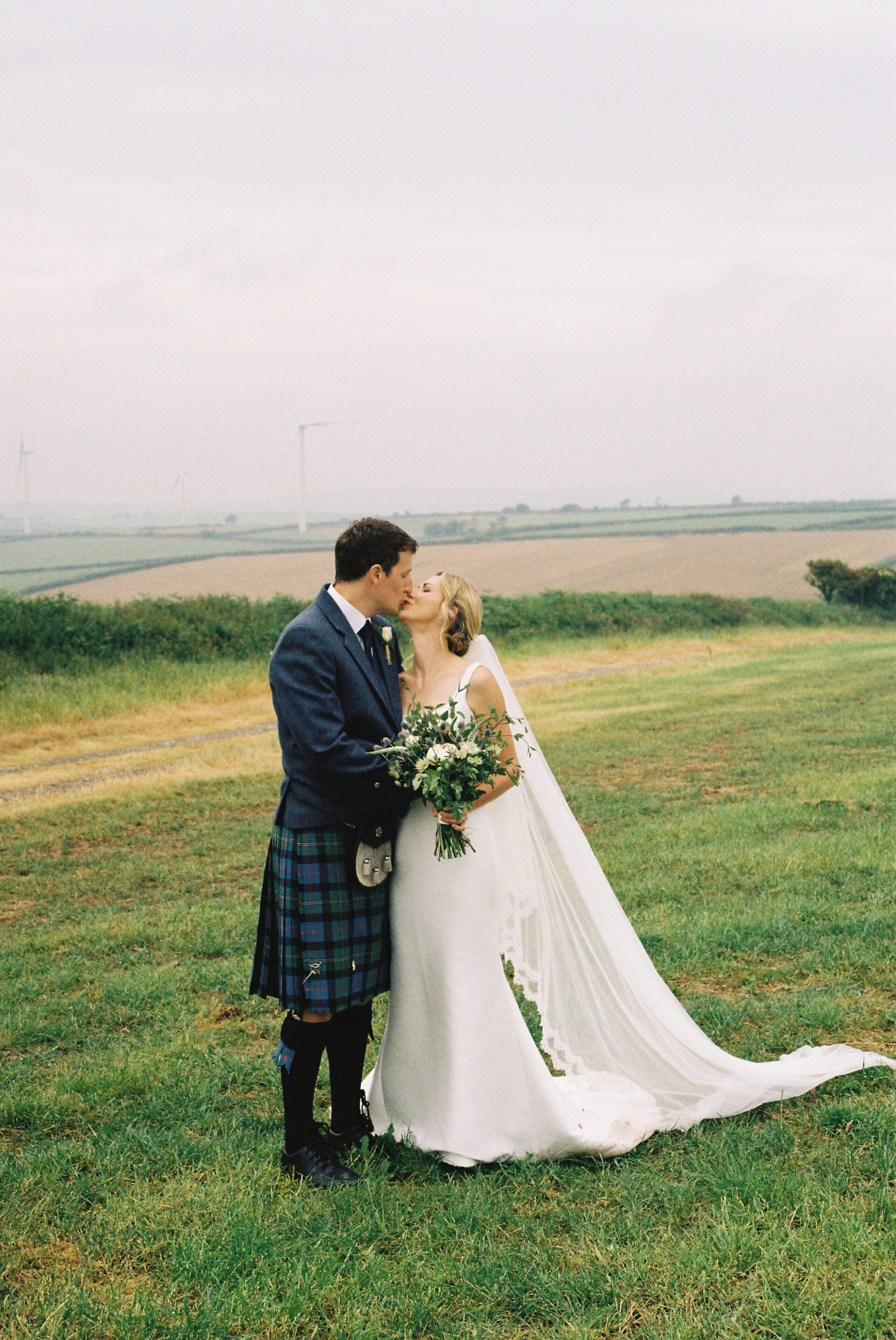 A 35mm film portrait of the bride and groom kissing