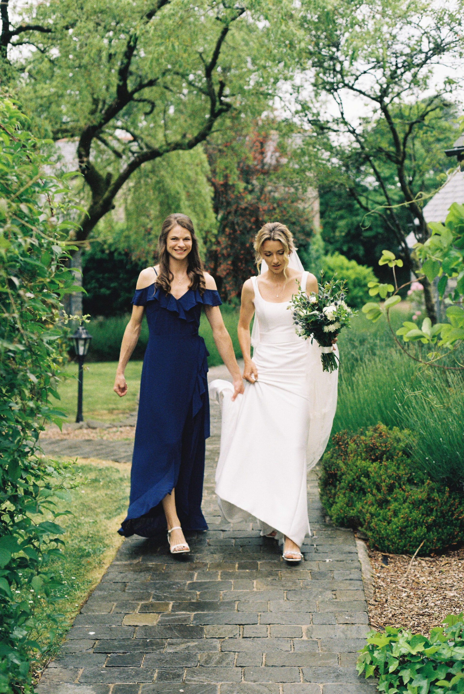 The bride walks with her bridesmaid on 35mm film