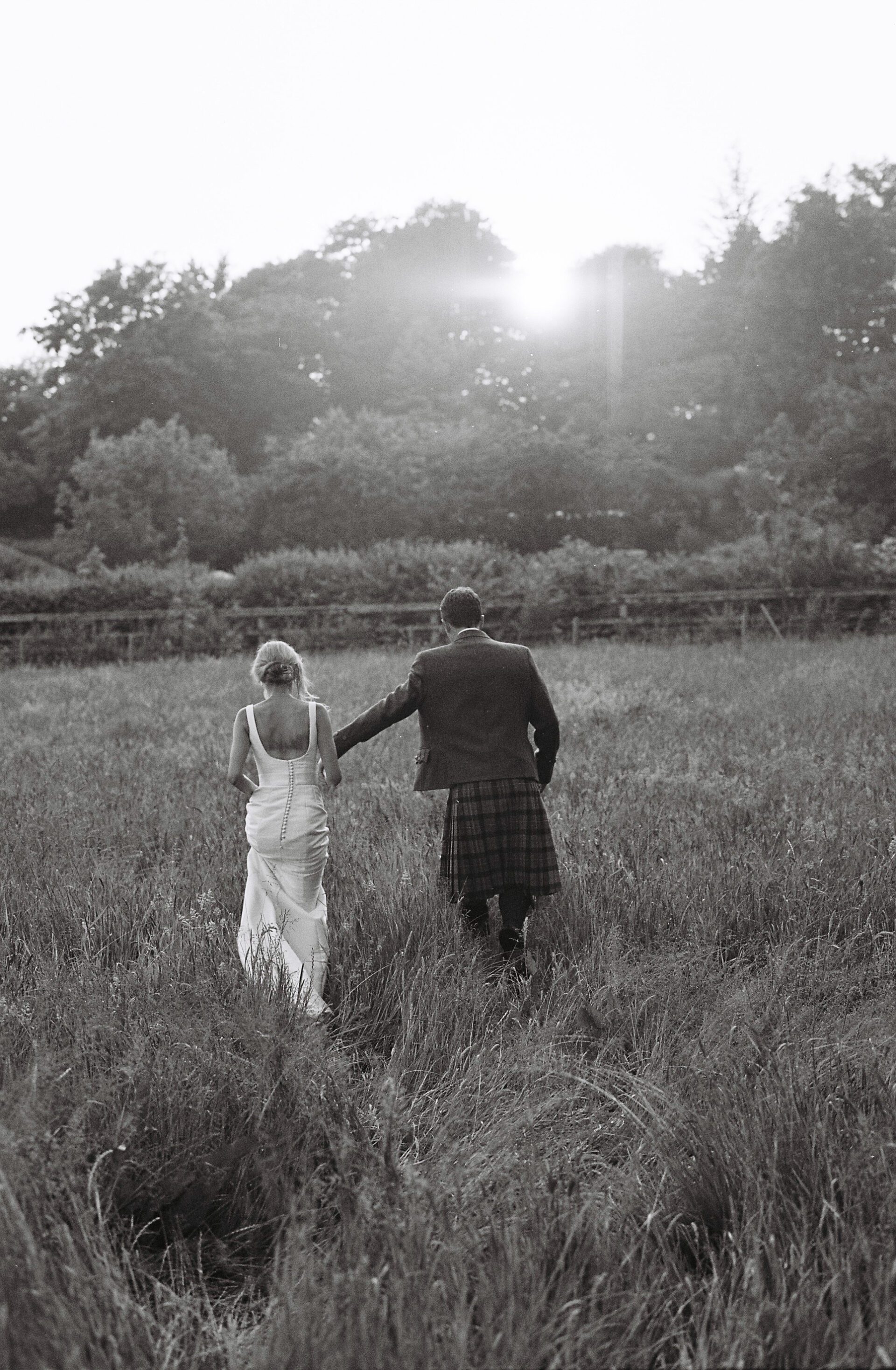 A couple walking through a field during golden hour, captured on 35mm film