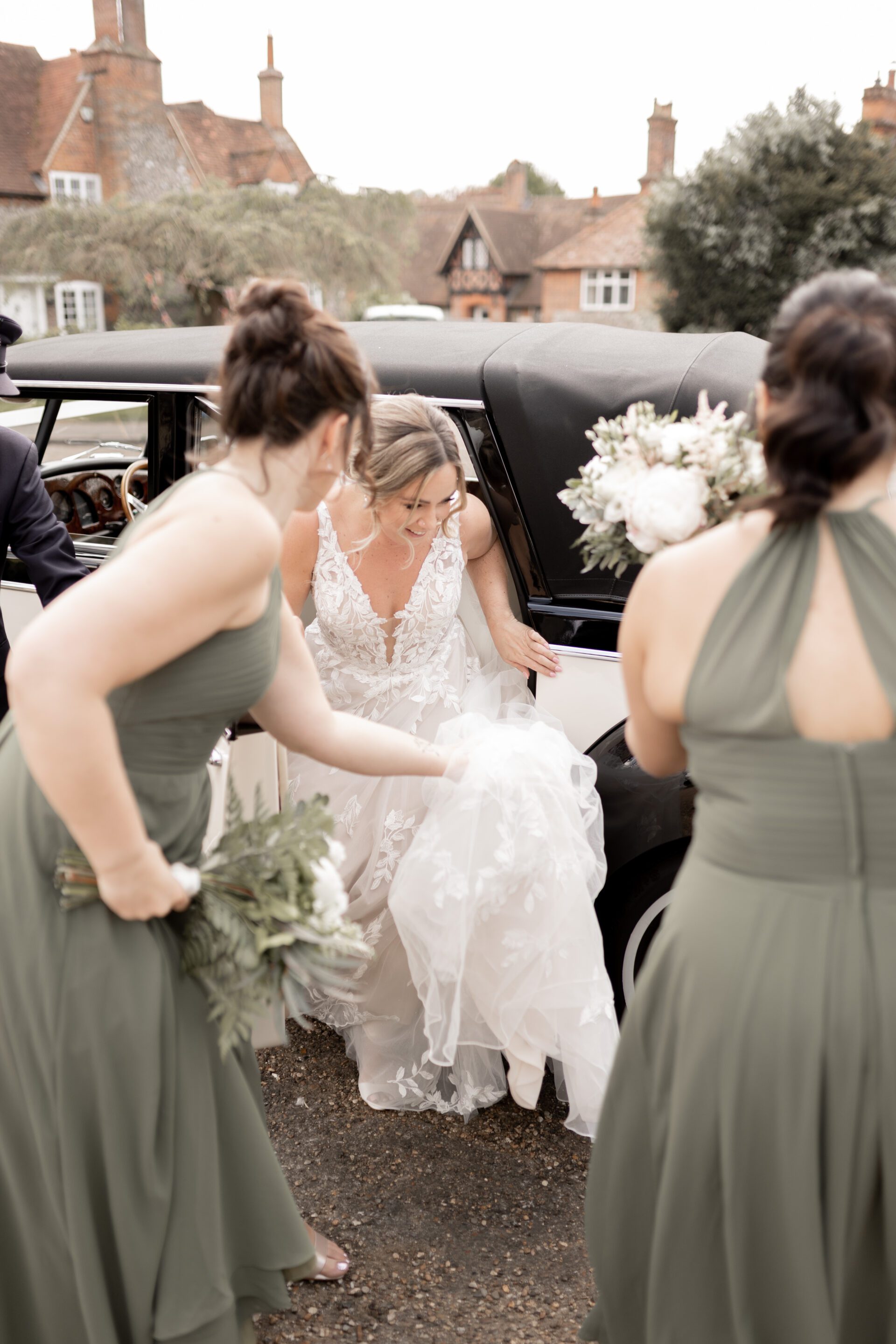 The bride gets out of the vintage wedding car before her wedding ceremony in Oxfordshire