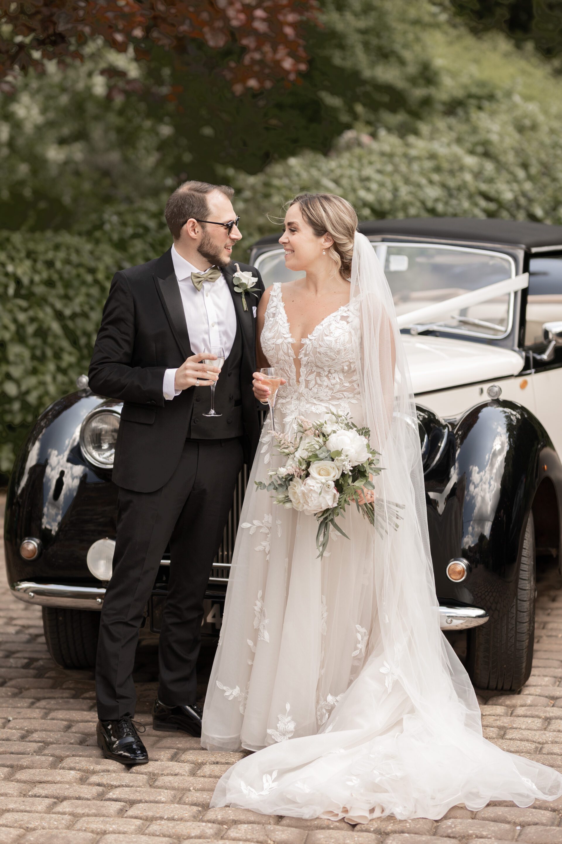 The bride and groom stop in front of their vintage wedding car