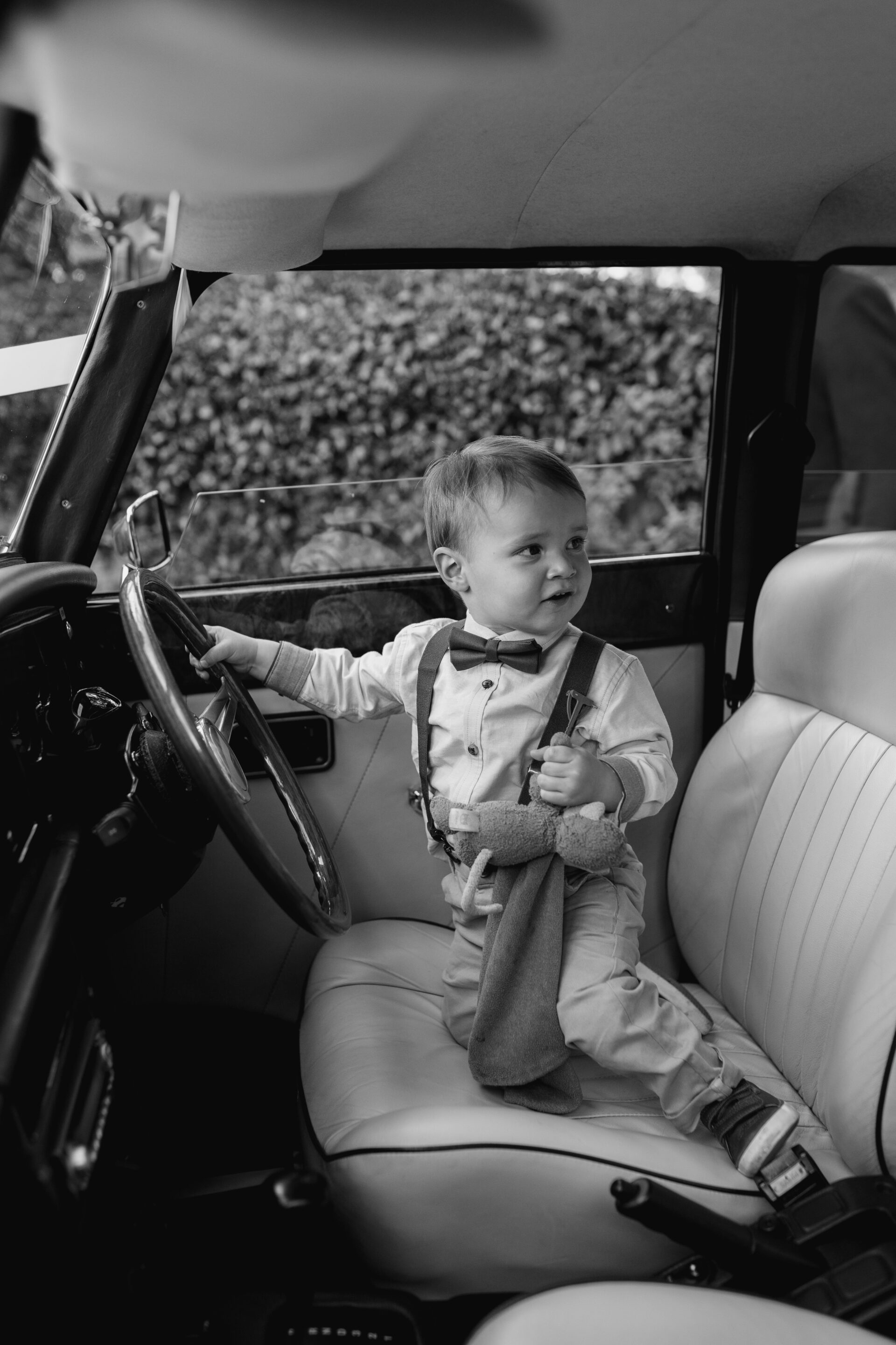 A young wedding guest enjoys exploring the vintage wedding car
