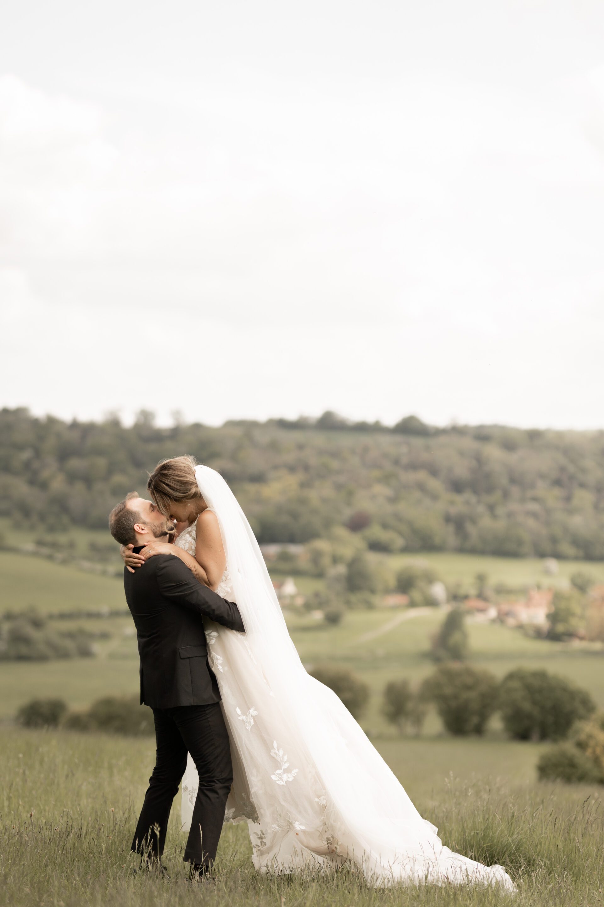 The groom embraces his bride at Old Luxters Barn in Oxfordshire