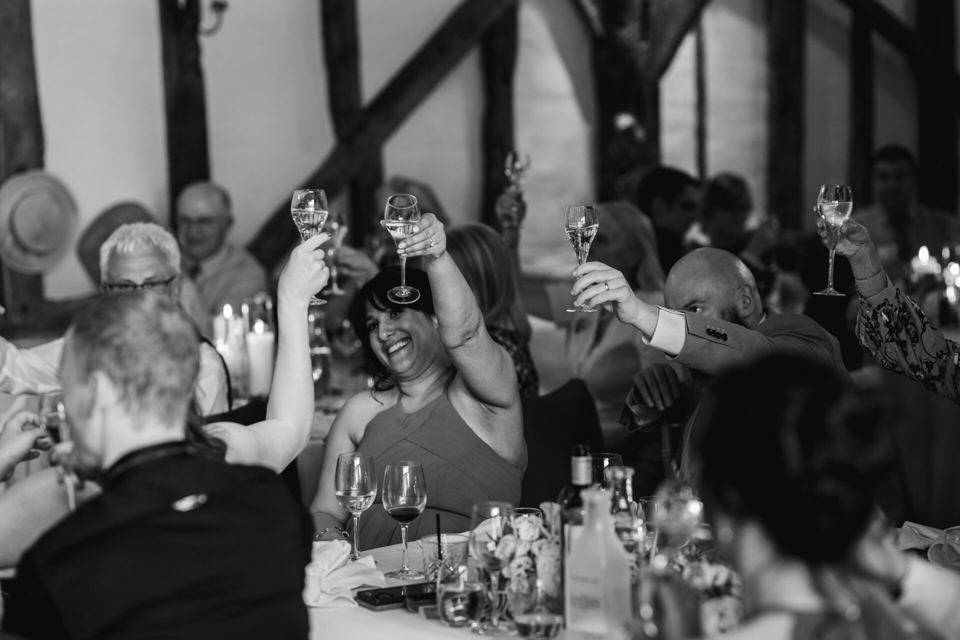 Wedding guests raise their glasses for a toast at Old Luxters Barn wedding venue in Oxfordshire
