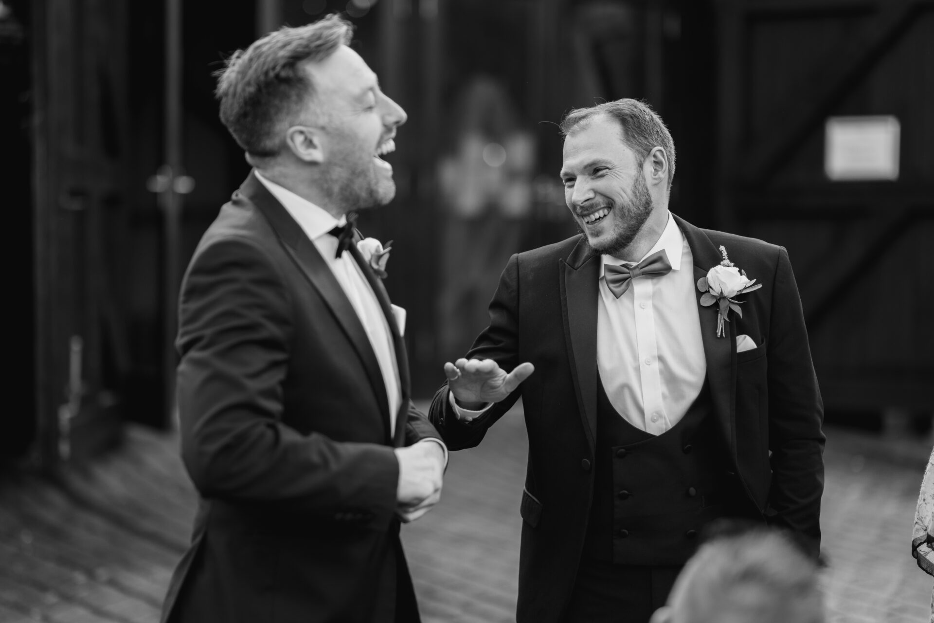 The groom and his best man share a joke at Old Luxters Barn wedding venue in Oxfordshire