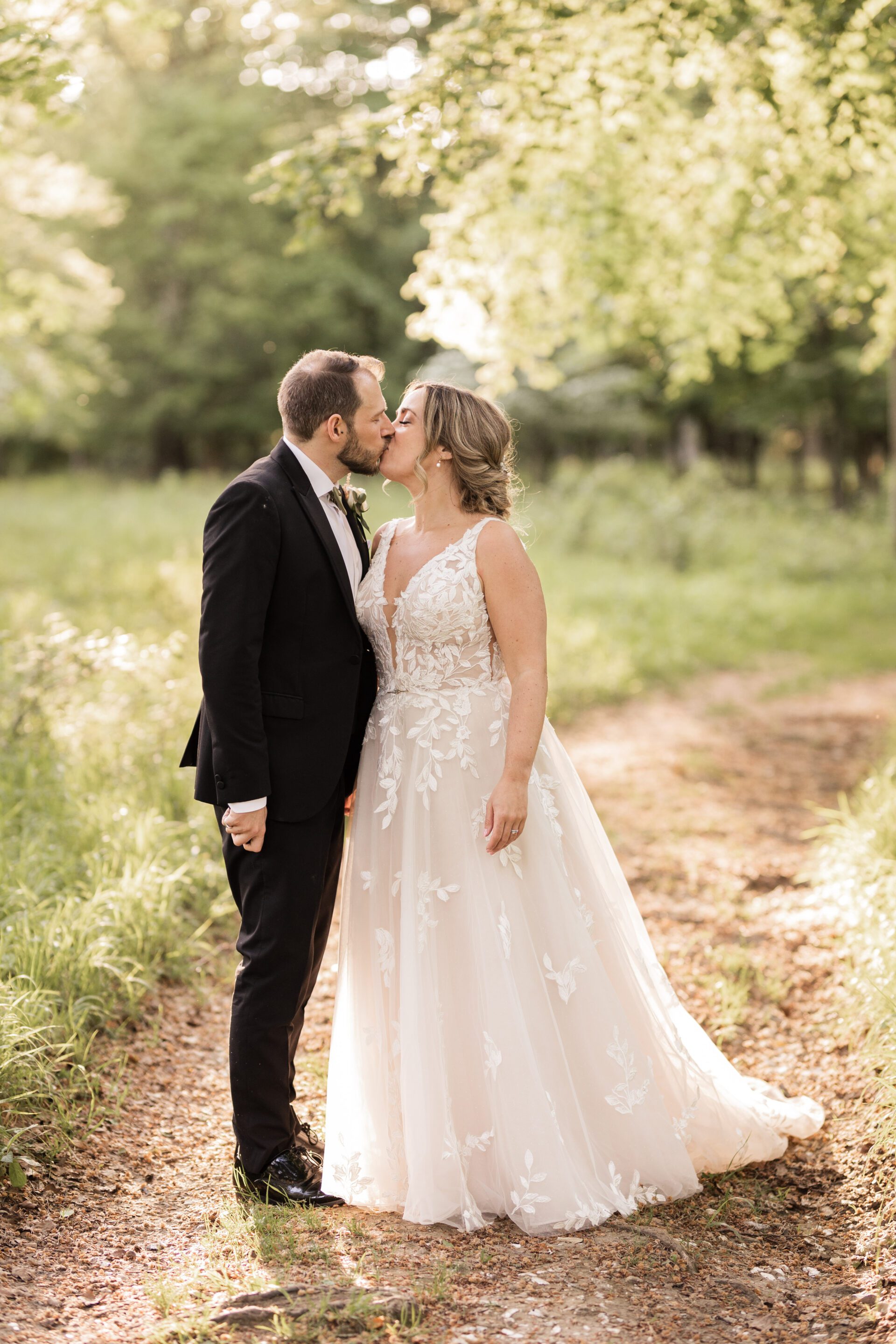 The bride and groom share a kiss during golden hour at their barn wedding