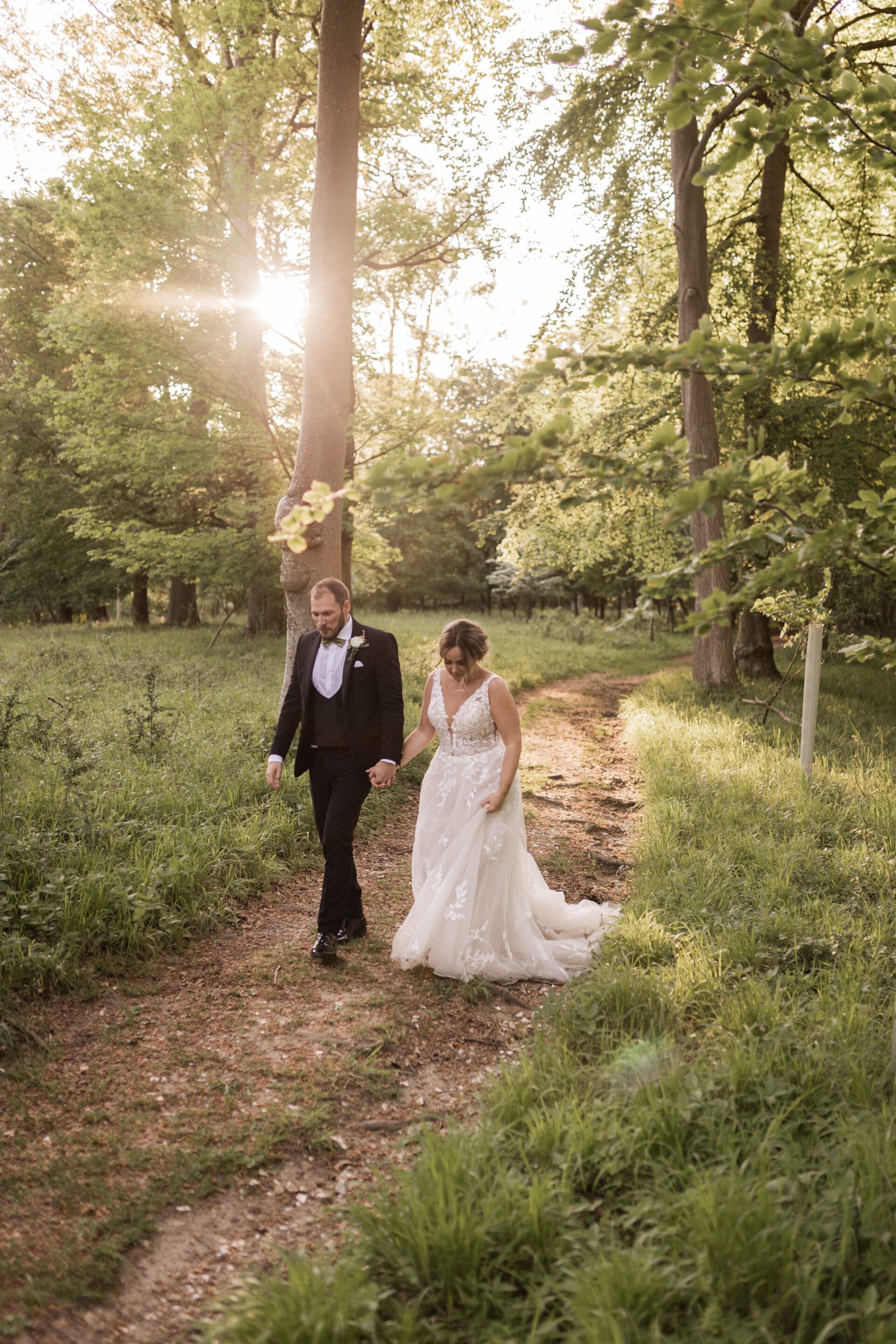 The bride and groom walk hand in hand during their golden hour couples photos