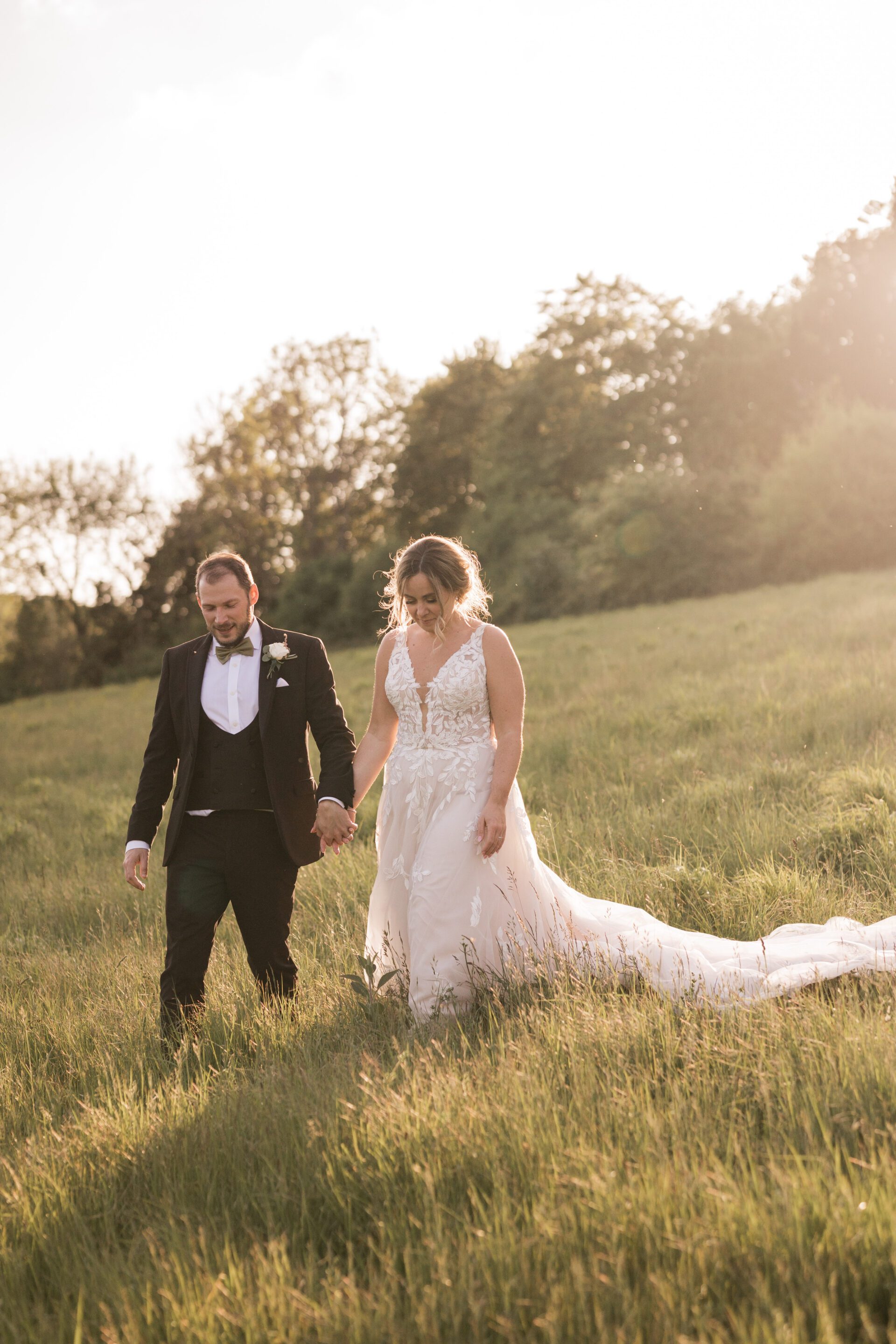 The bride and groom walk hand in hand during golden hour