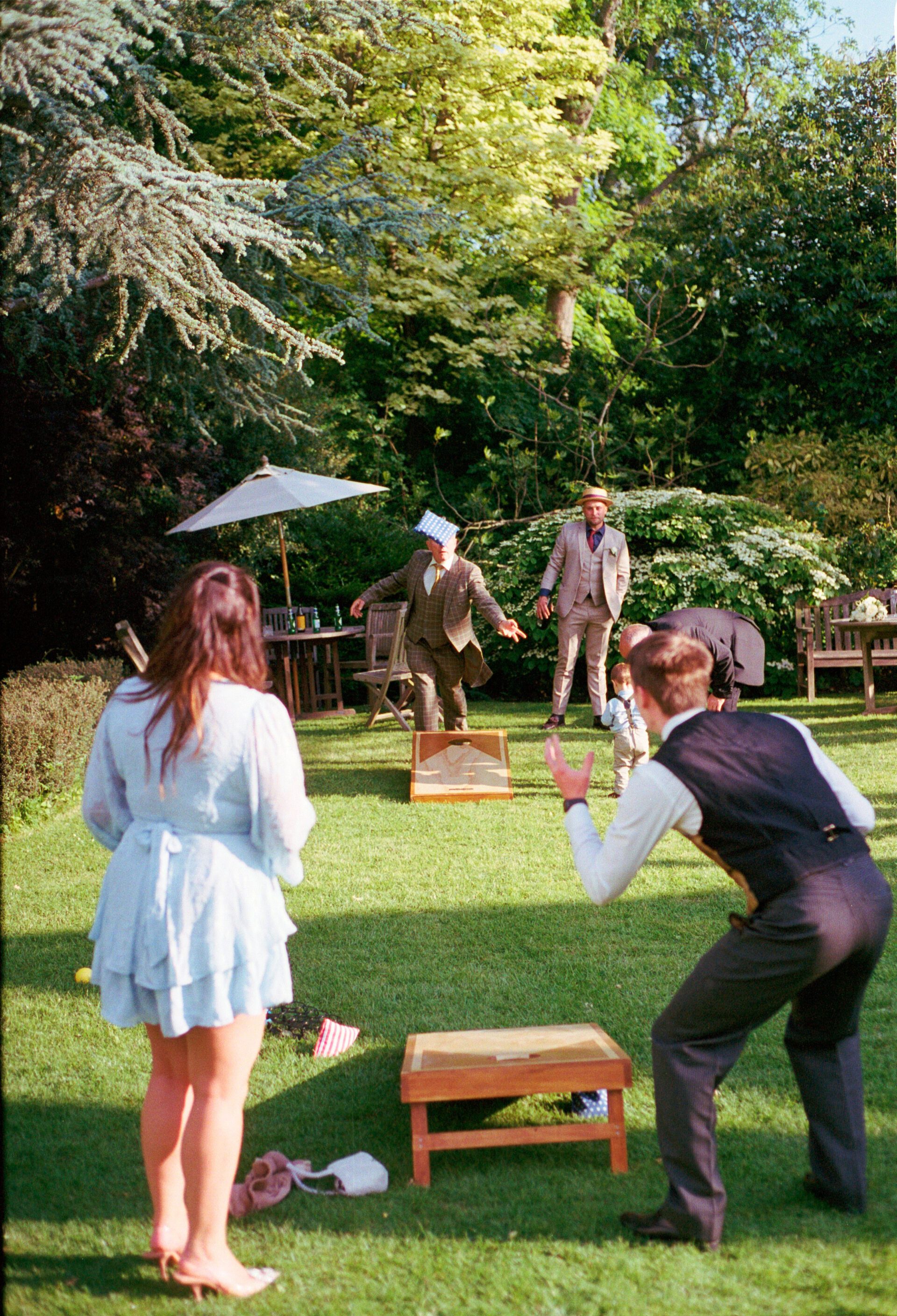 Wedding guests enjoy garden games at Old Luxters barn, captured on 35mm film