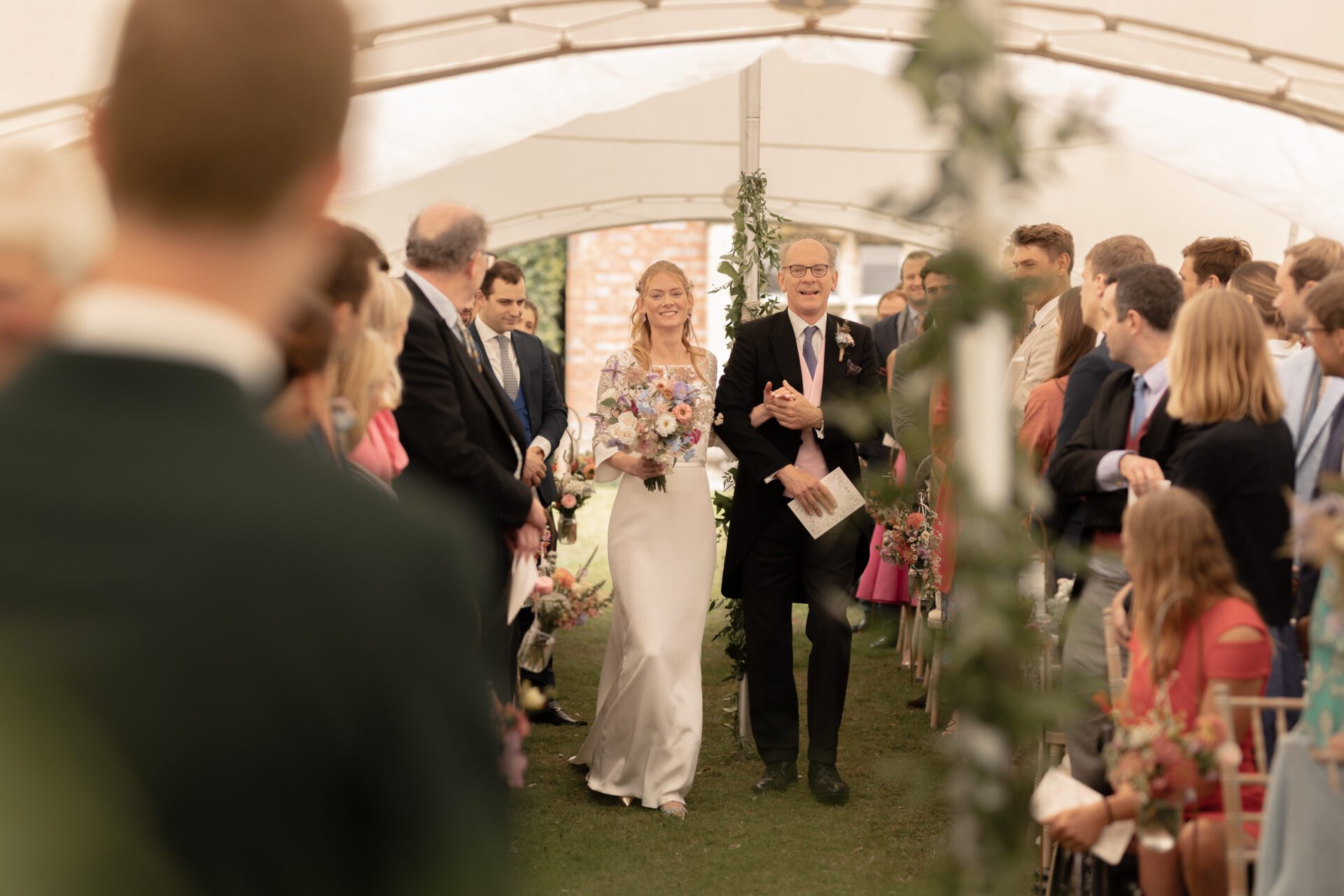 The bride and her father walk down the aisle at Brickwall House