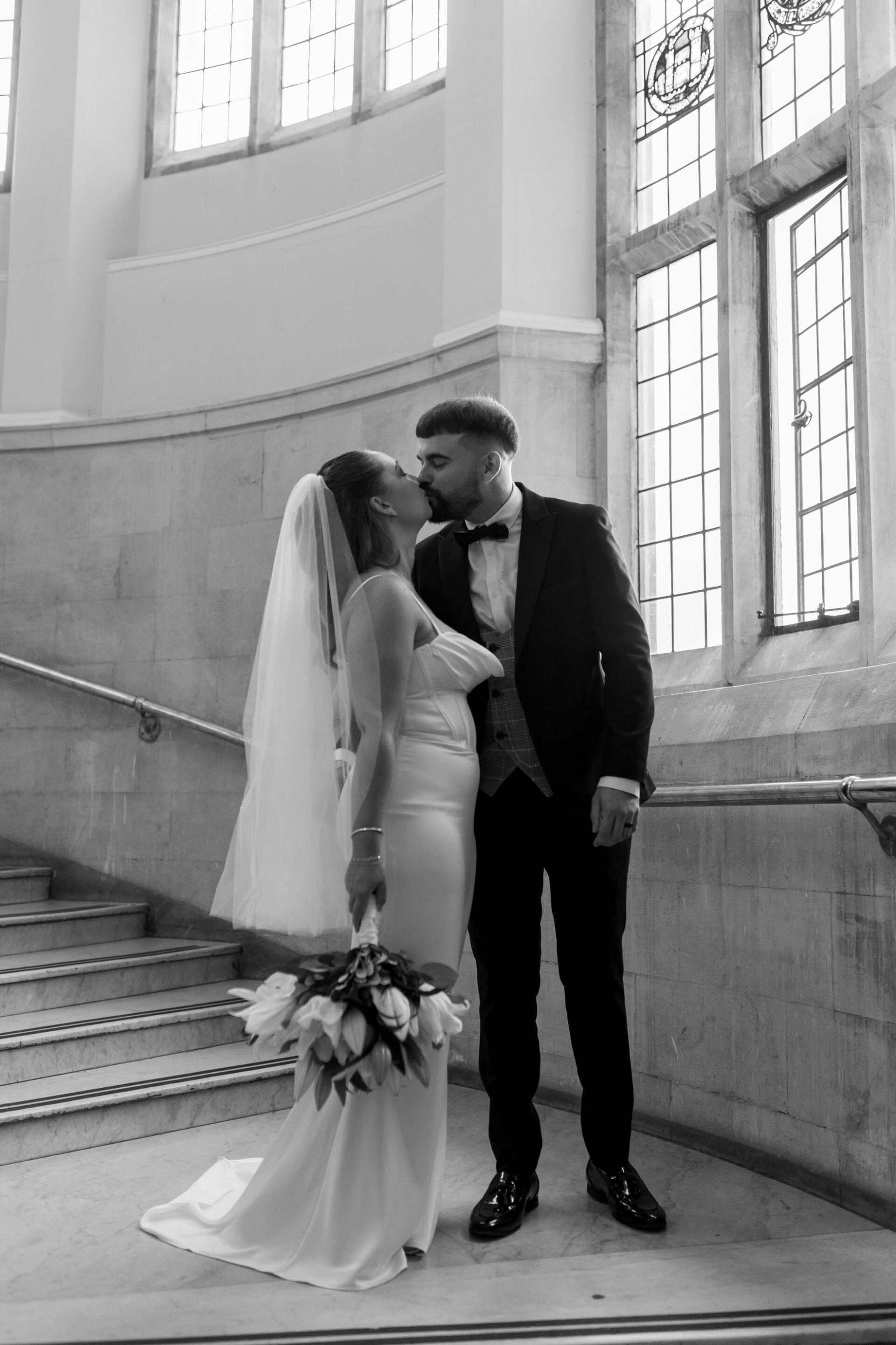 The bride and groom stop for kiss during their couple portrait session at Bristol Library