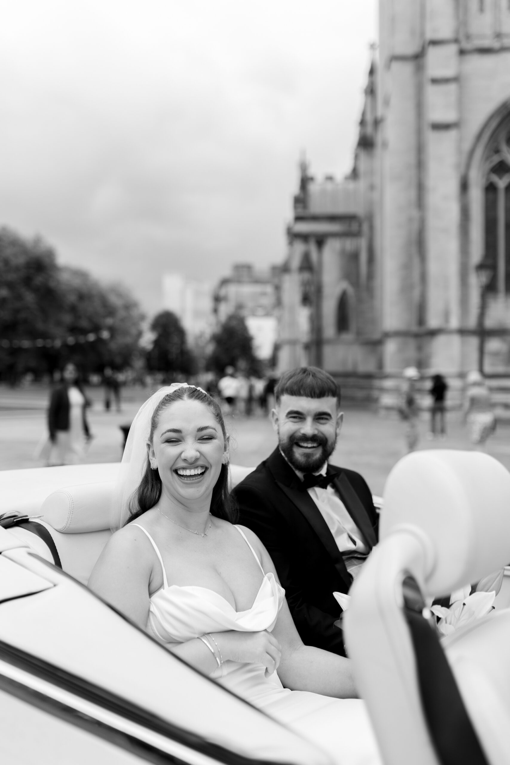 A black and white couple portrait in a classic vintage wedding car