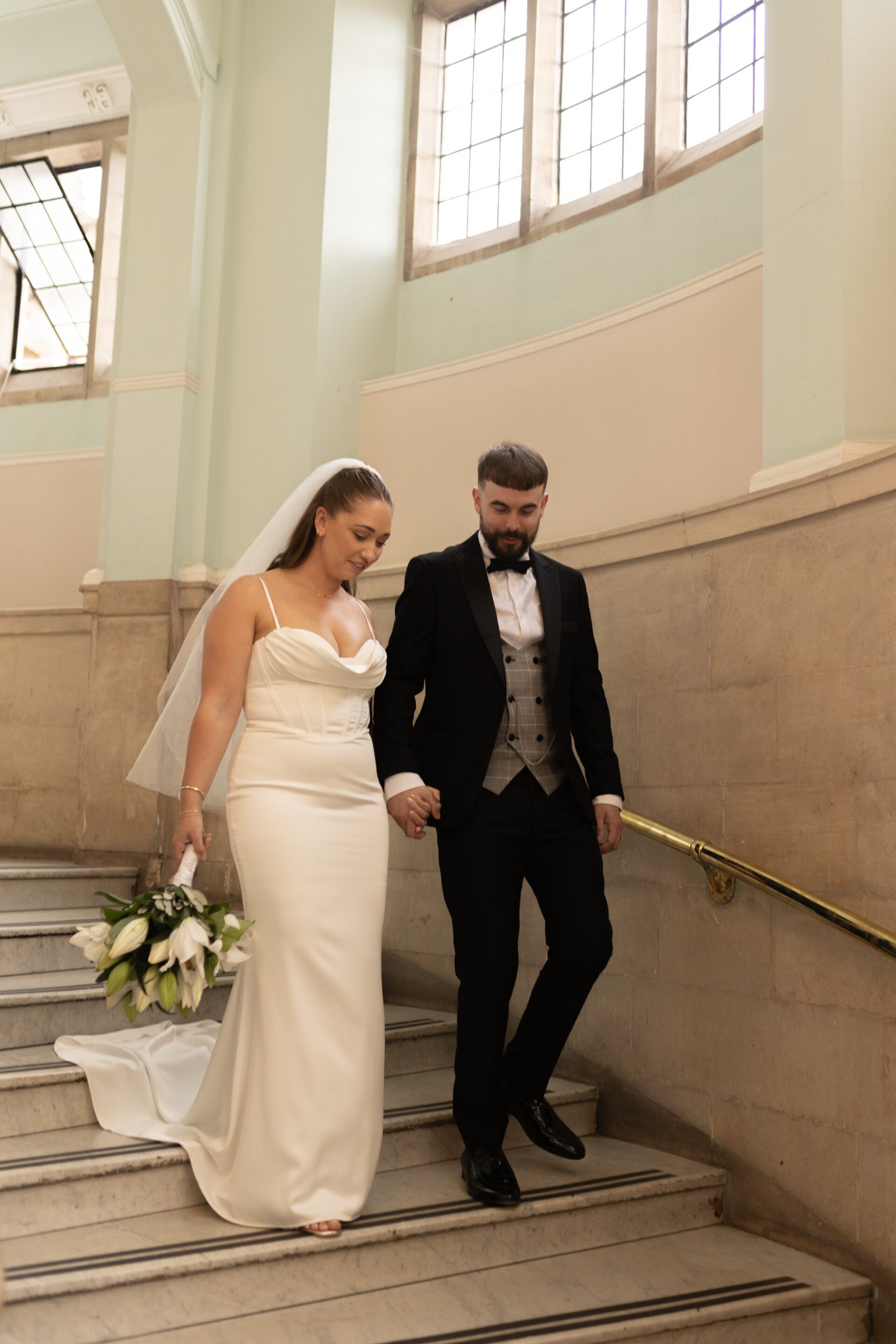The bride and groom walk down the stairs during their couple portrait session at Bristol Library
