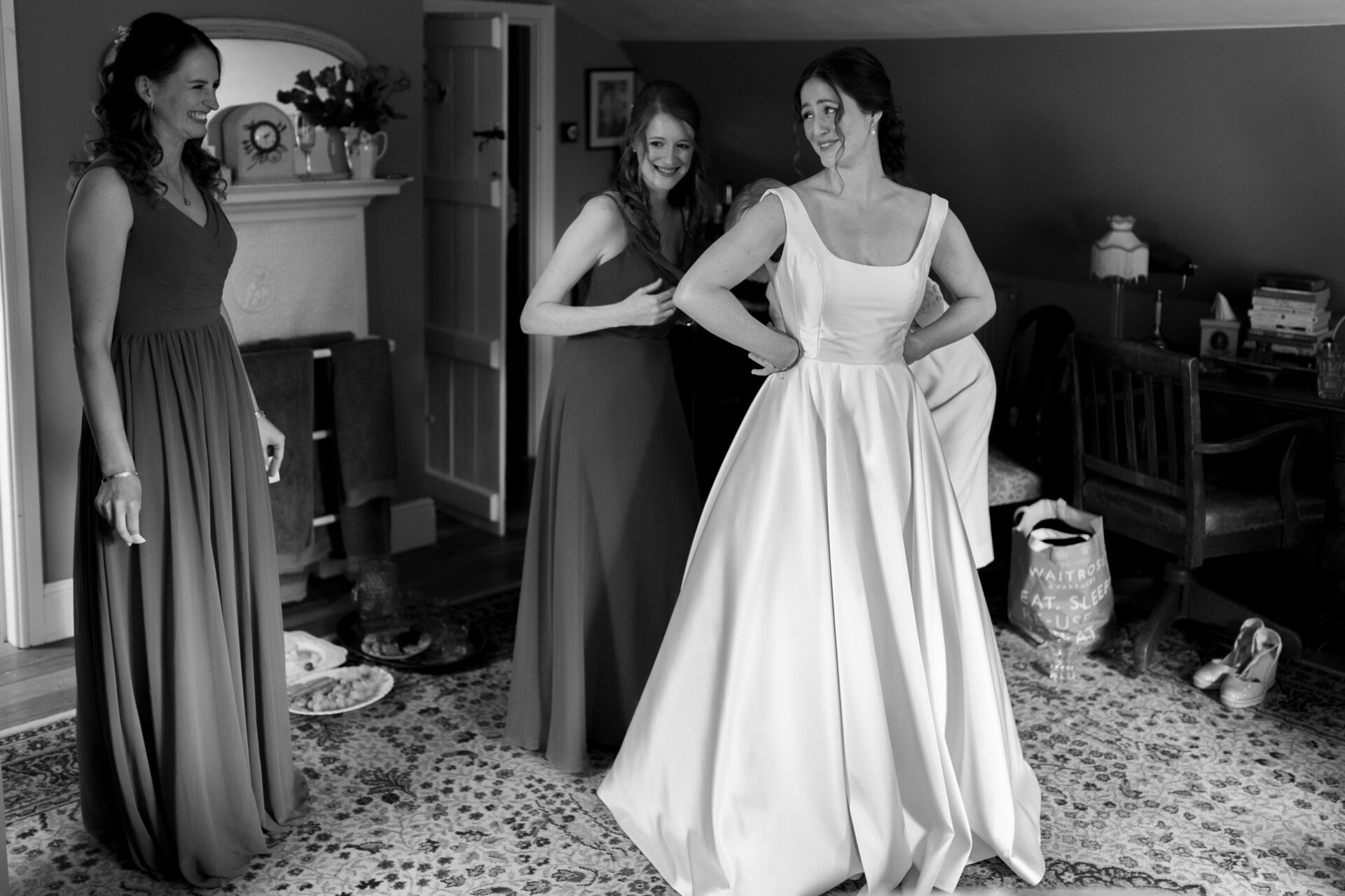 The bridesmaids help the bride get into her Millie Couture wedding dress