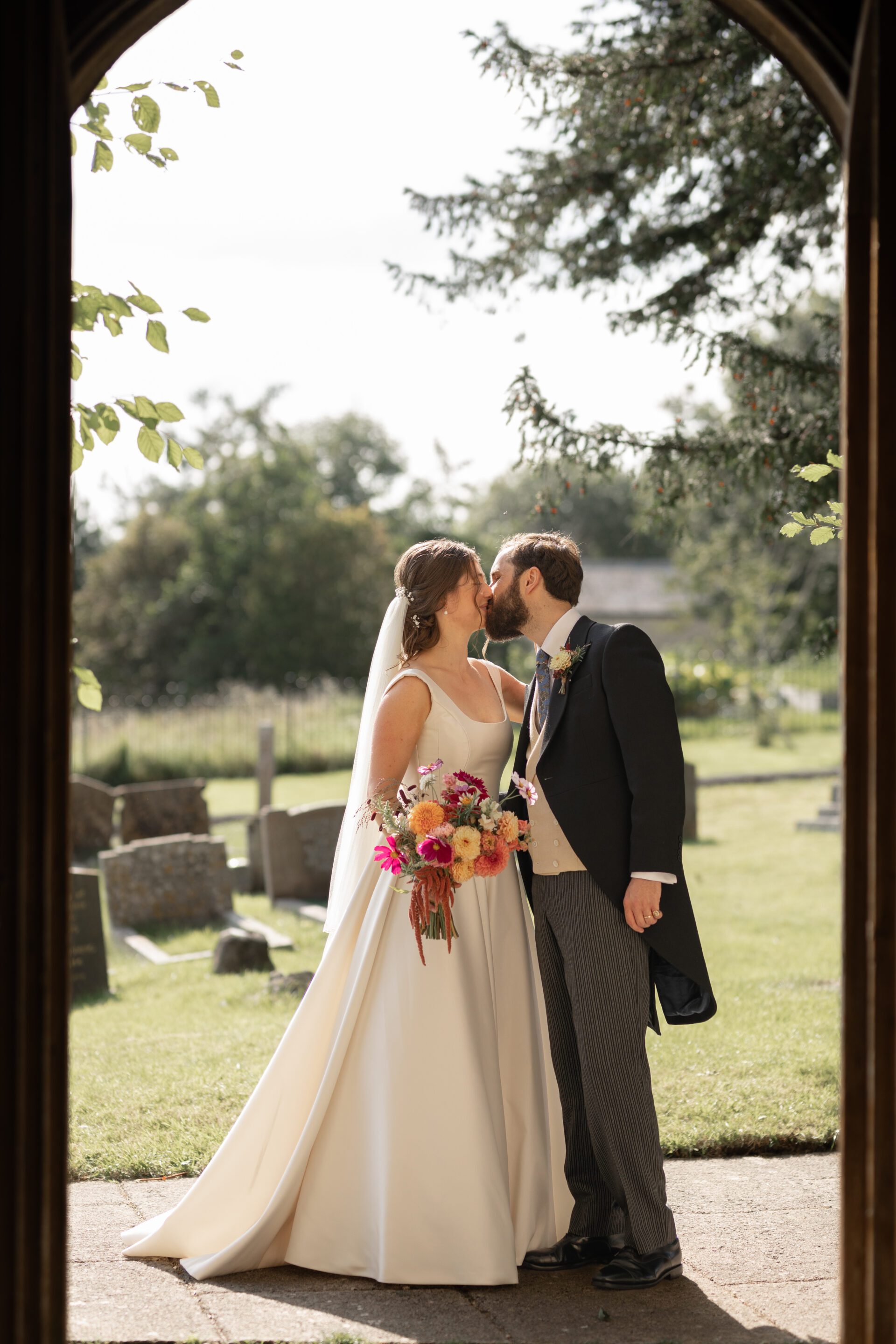 The bride and groom share a kiss after their after their Somerset church wedding ceremony