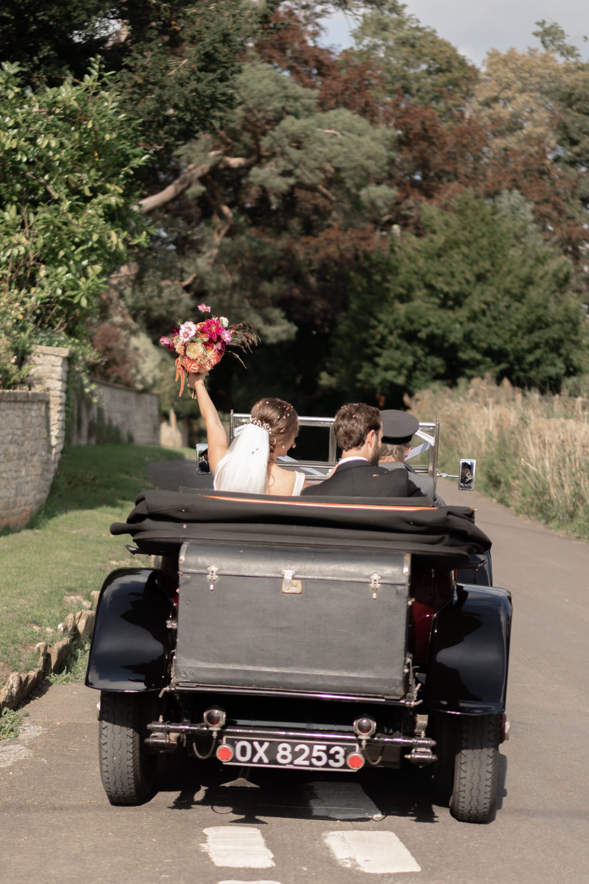 The bride and groom depart their Somerset church wedding in a vintage wedding car