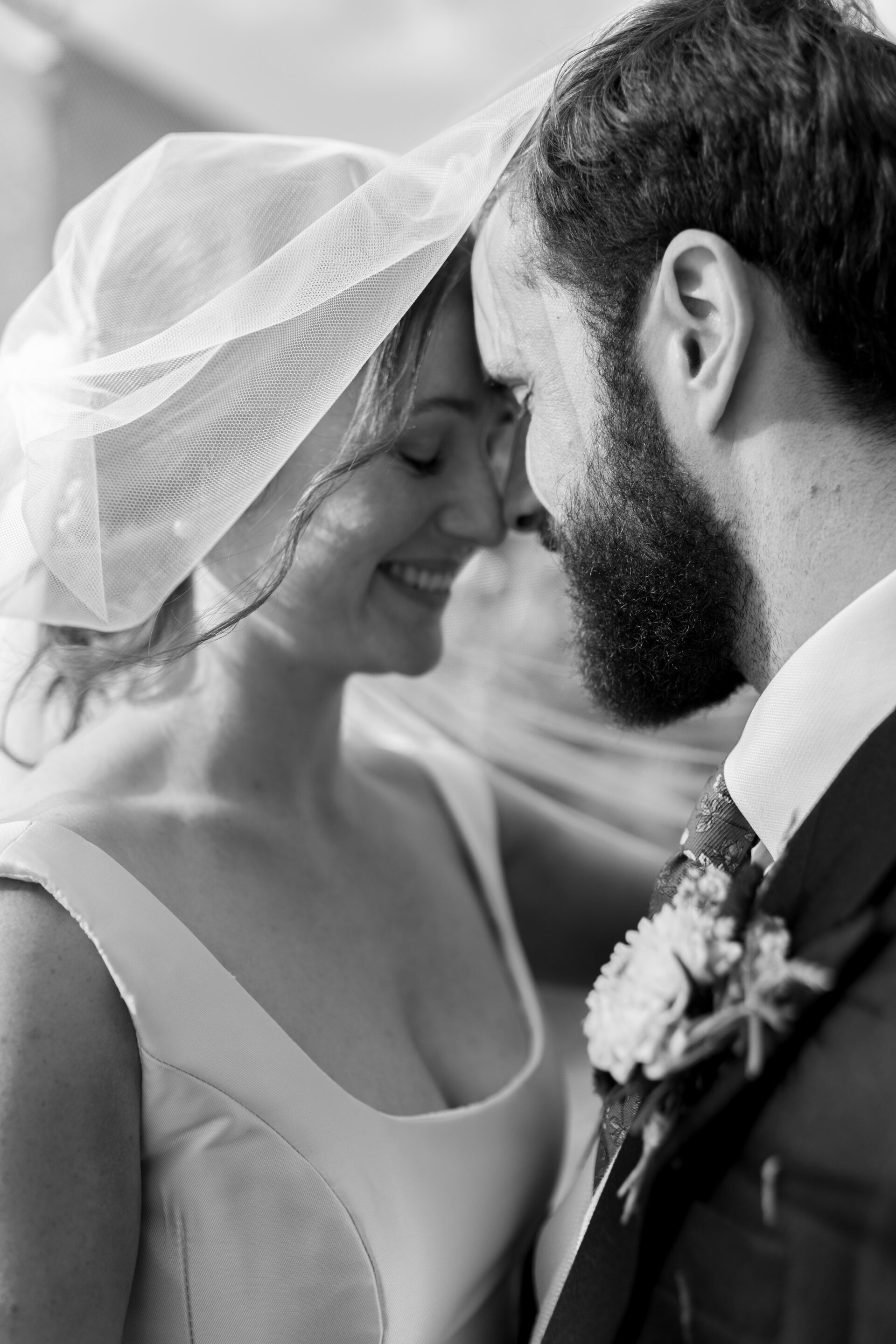 The bride and groom share an embrace under the veil during their couples portrait session