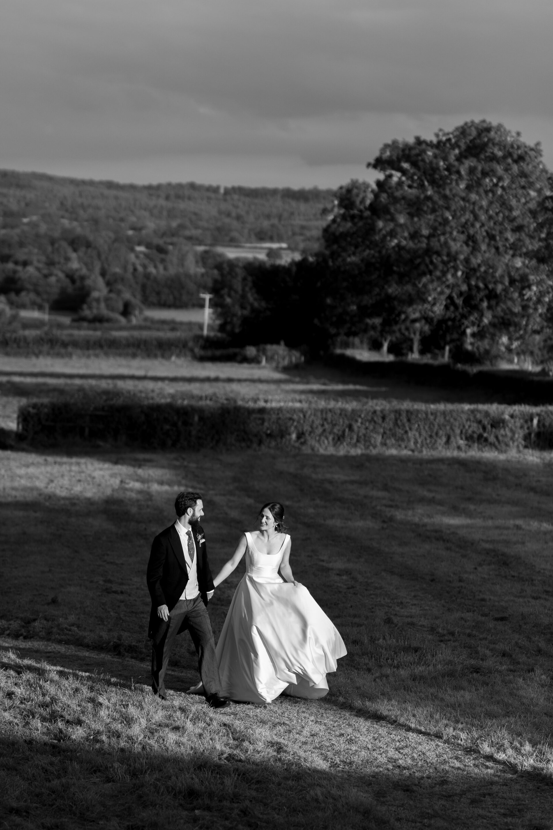 The bride and groom walk back towards the party at their Somerset marquee wedding