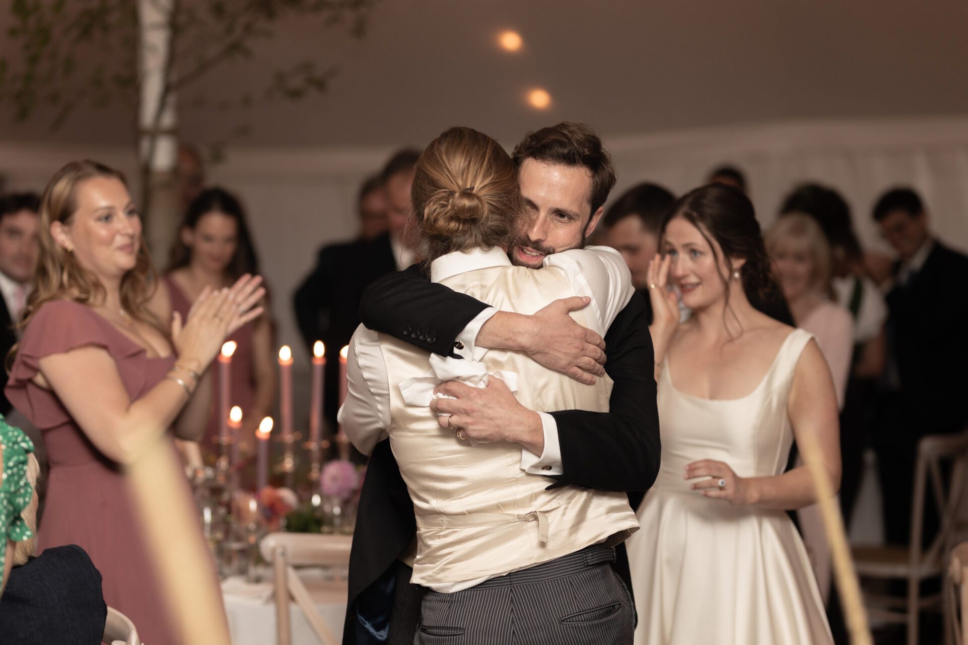 The groom embraces a friend at his Somerset marquee wedding