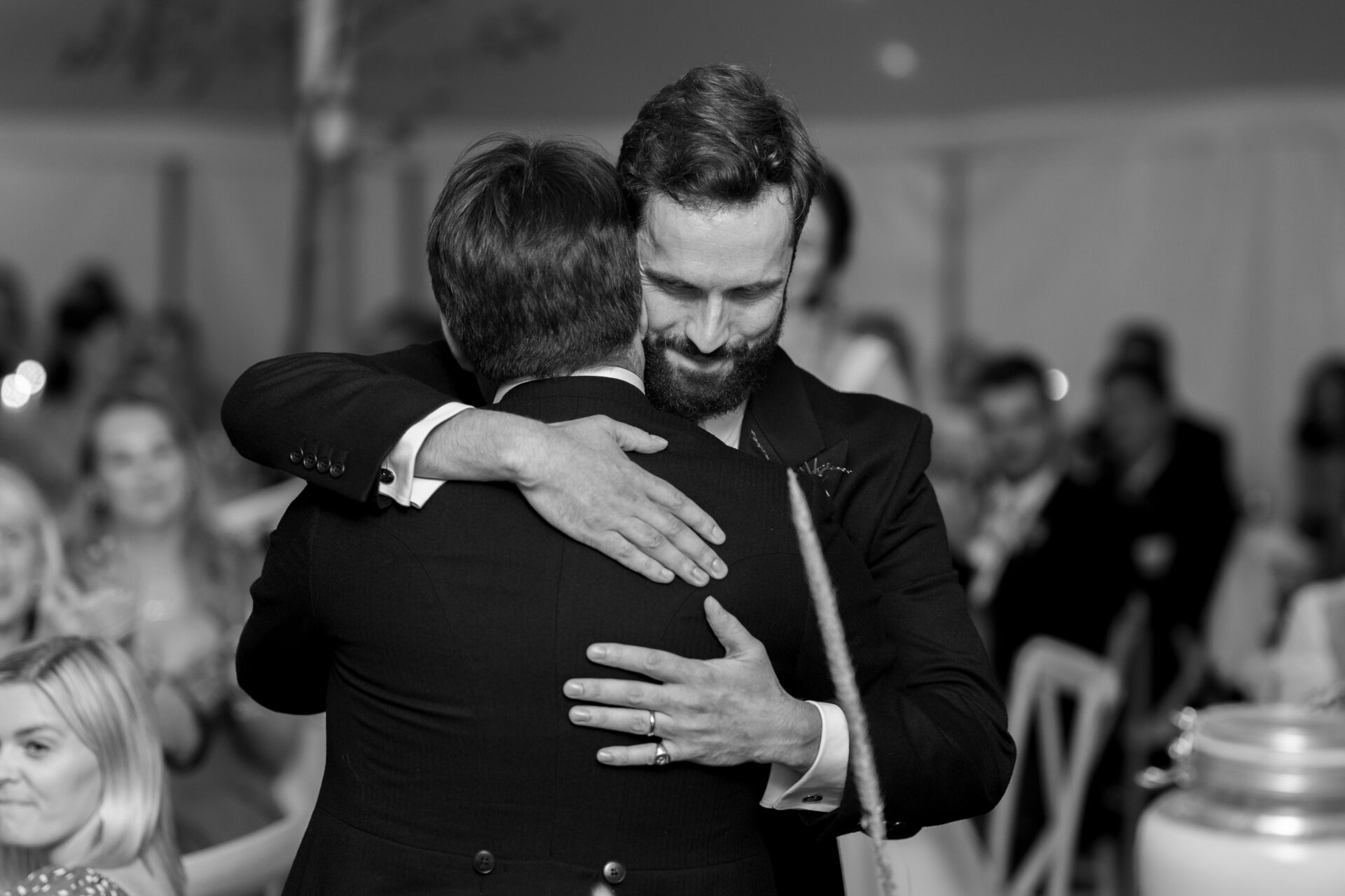 The groom embraces a friend during his Somerset marquee wedding