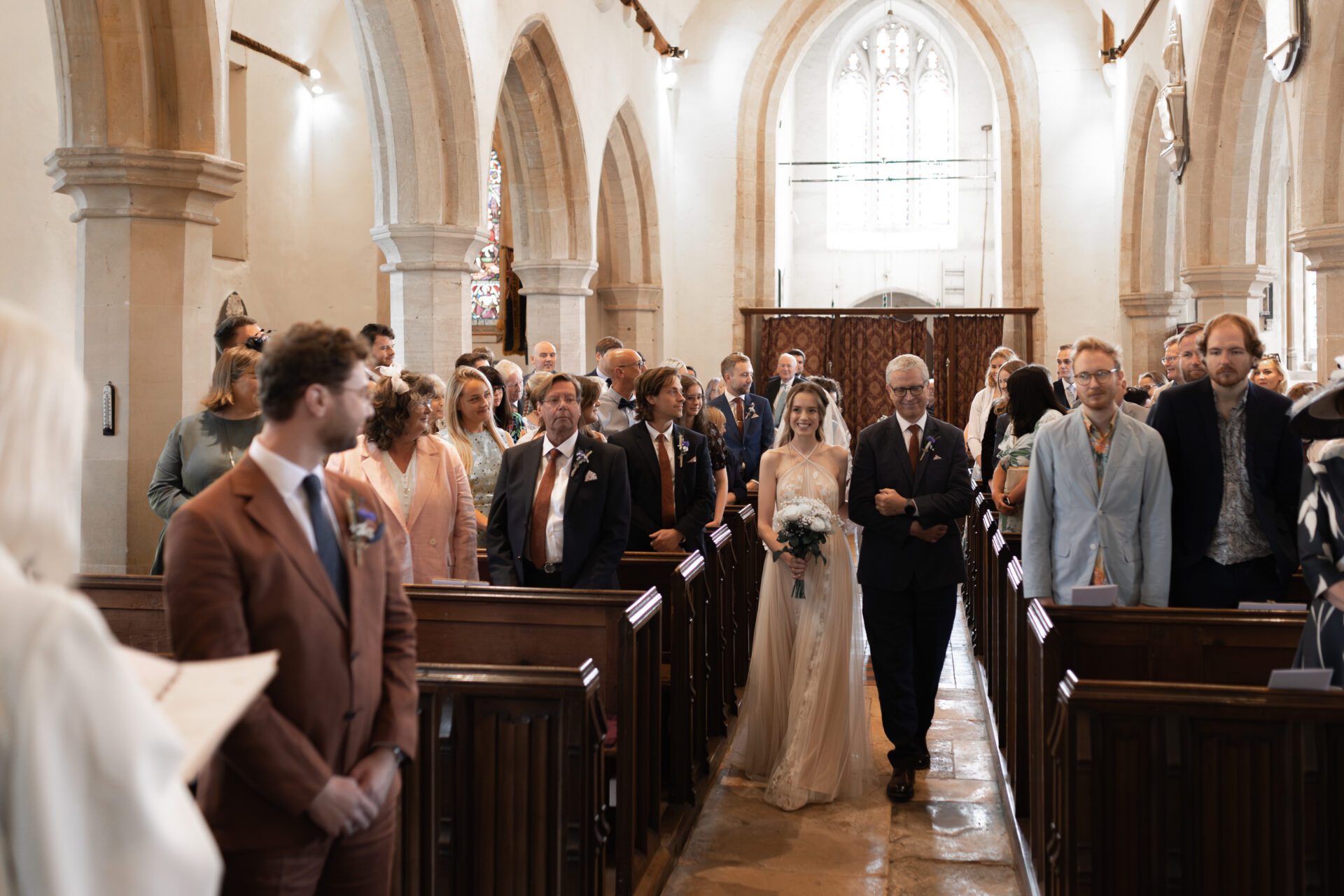 The bride walks down the aisle with her father for her Gloucestershire wedding
