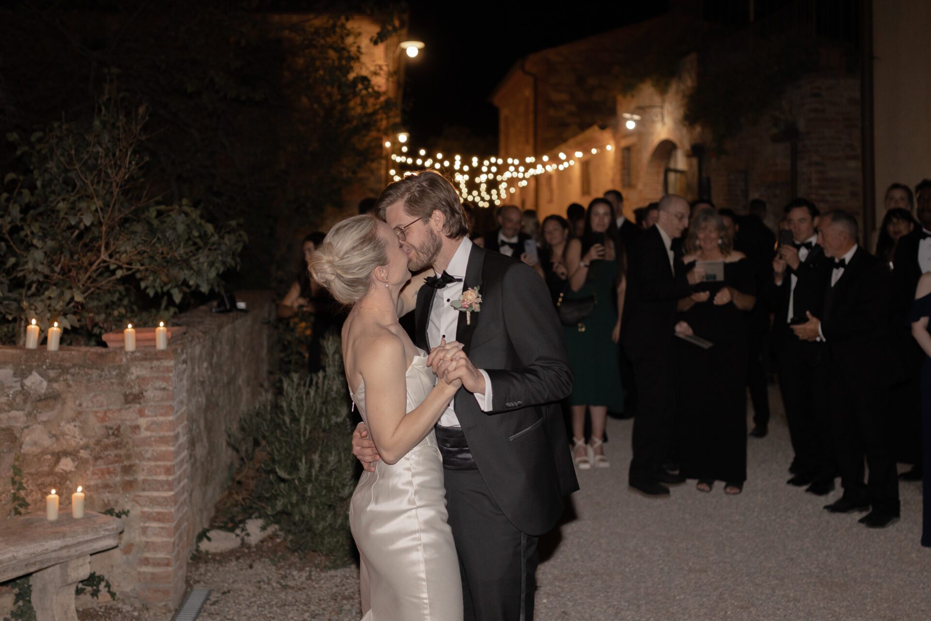 The bride and groom share their first dance in the Tuscan wedding venue courtyard surrounded by lights and candles