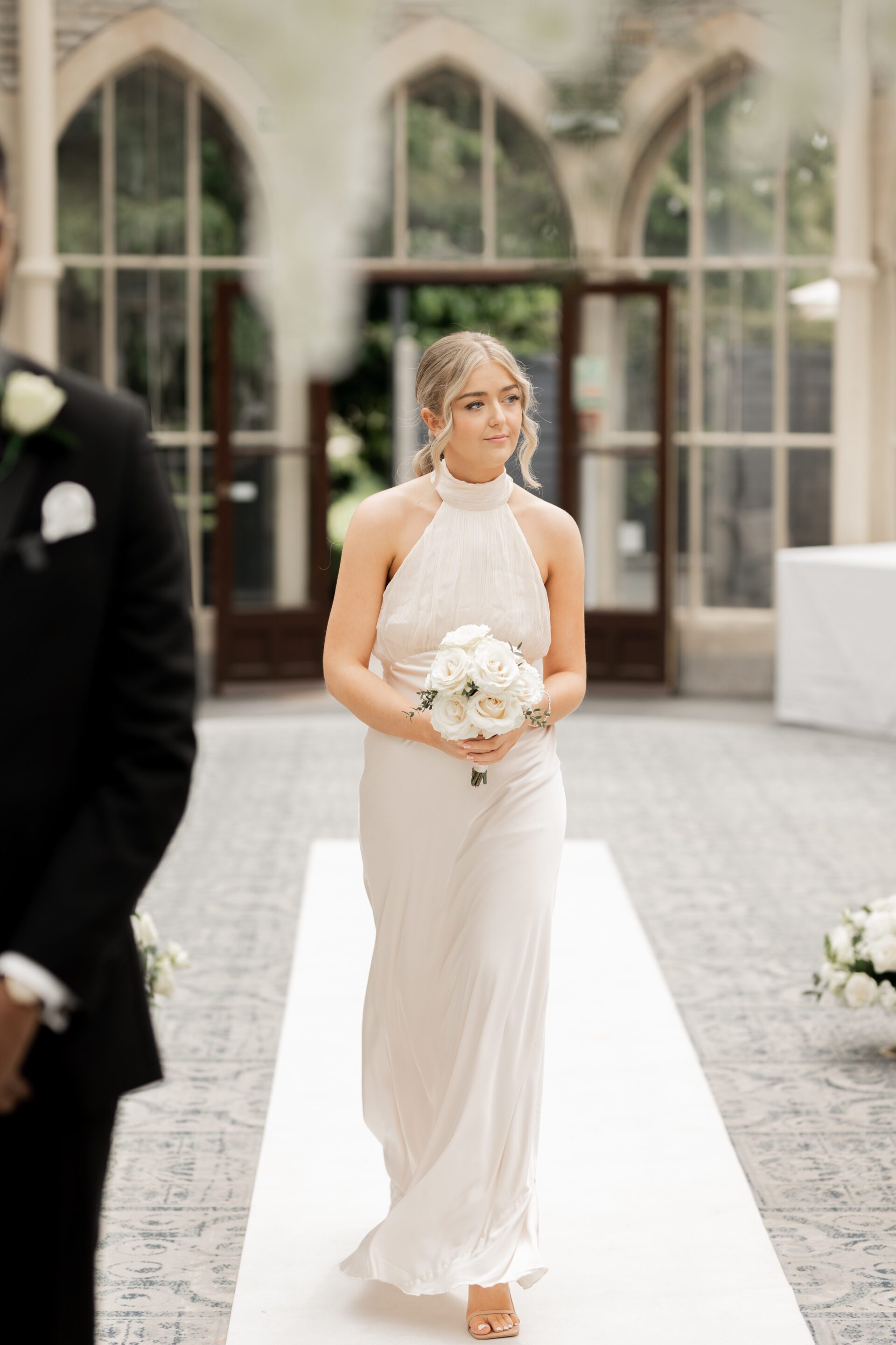 A bridesmaid walks down the aisle for the wedding ceremony in the Orangery at Tortworth Court